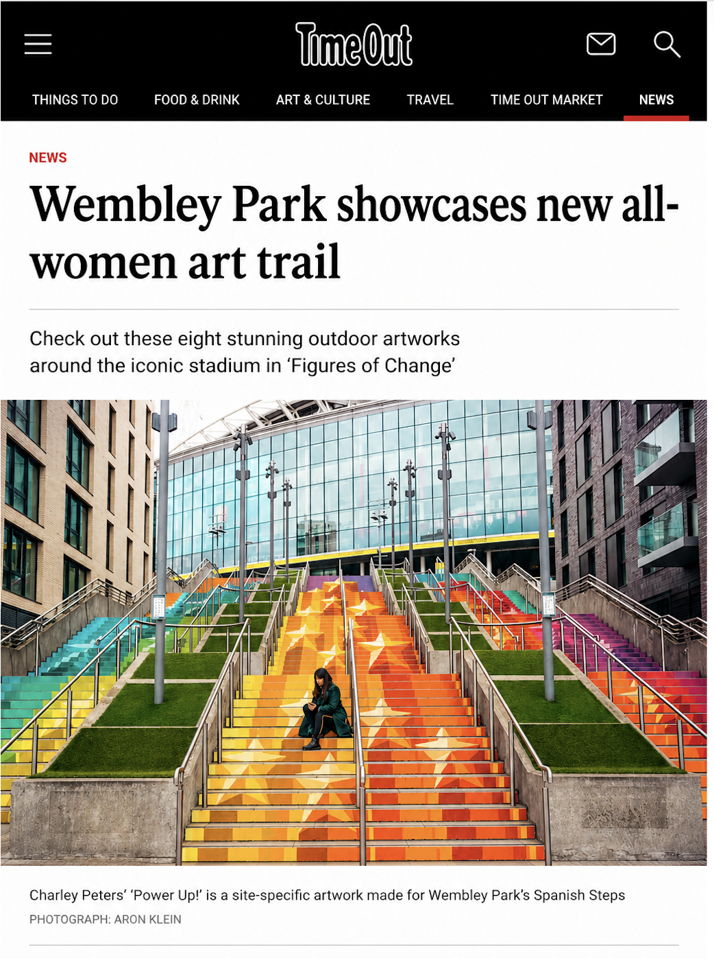 Colorful outdoor staircase with 8 runs, each painted in bright colors and decorated with stars, located at Wembley Park. A woman sits on the stairs, looking at her phone.