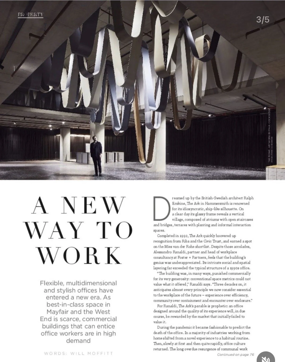 Interior shot of a modern office space with abstract hanging ribbons or strips on the ceiling, black wall panels, and a man dressed in a suit standing in the foreground