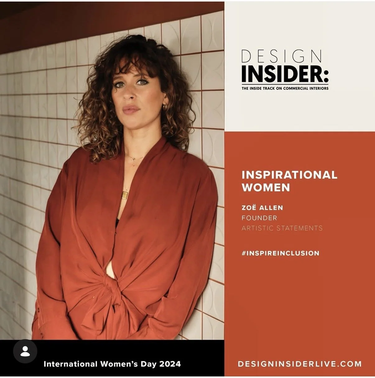 A woman with curly hair wearing a burnt orange blouse standing against a tiled wall.