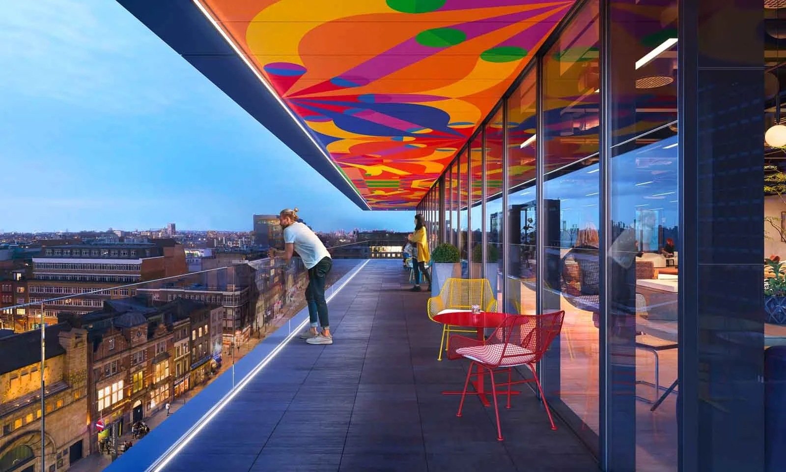 People on a rooftop terrace with colorful ceiling art, glass railing, and city view at dusk.