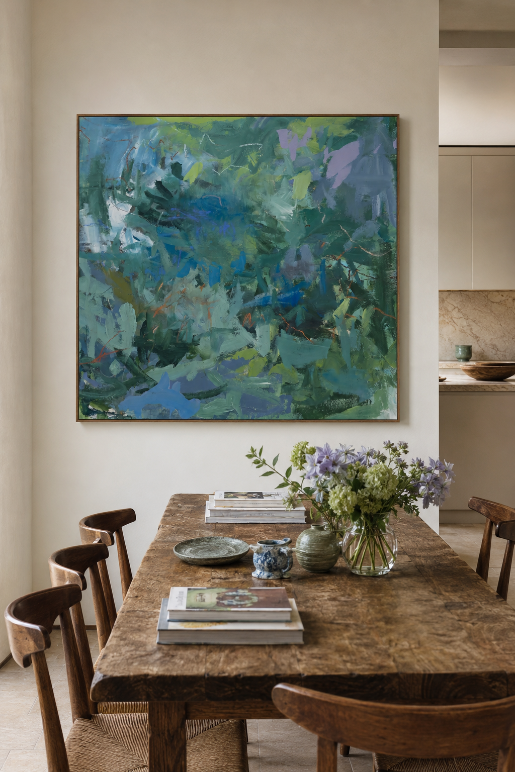 A wooden dining table with several chairs, a vase of purple and green flowers, and some magazines and ceramic bowls on it, in a room with a large abstract painting on the wall.
