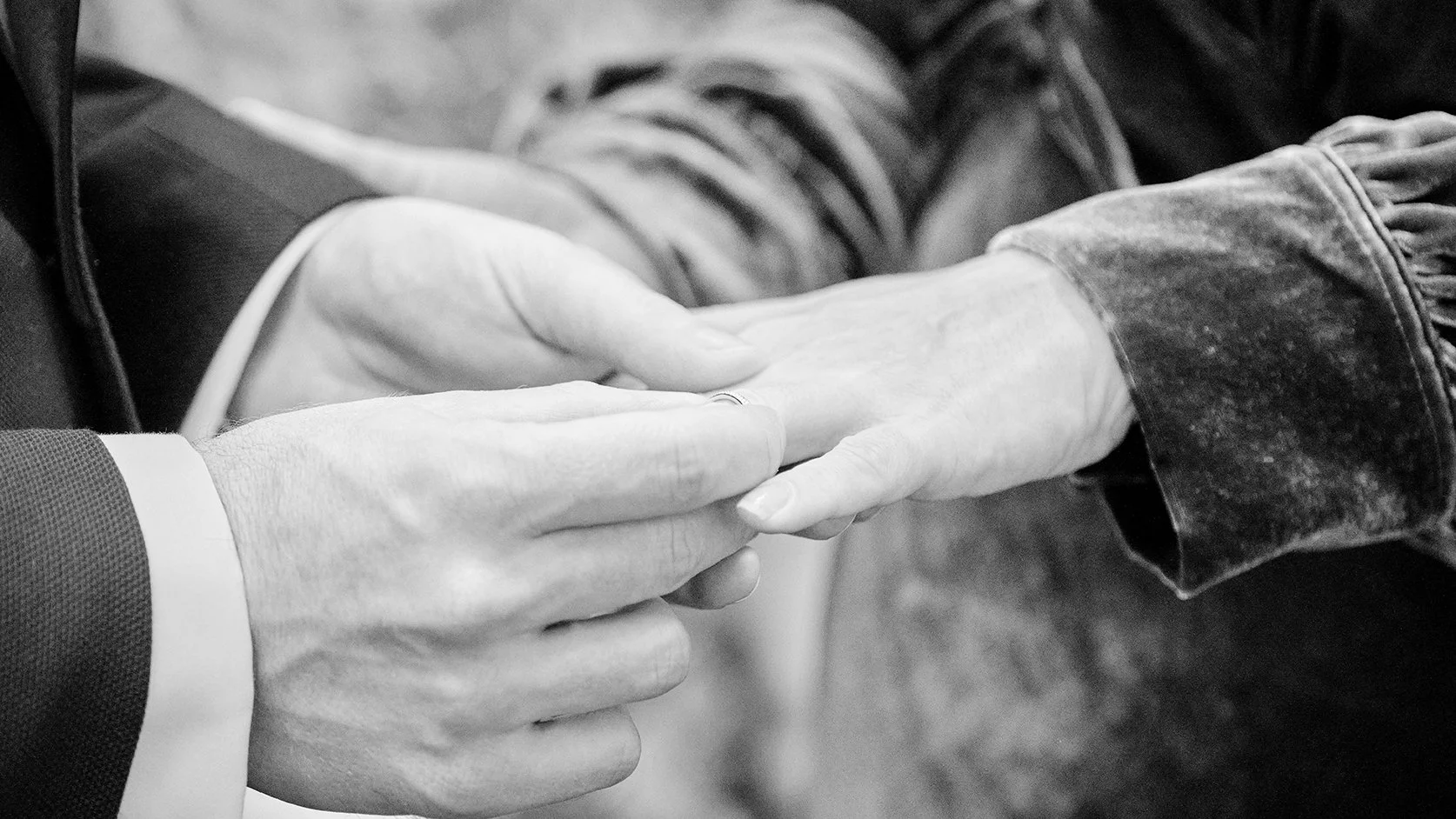 Close-up of two people holding hands, with one person touching the other's hand gently.
