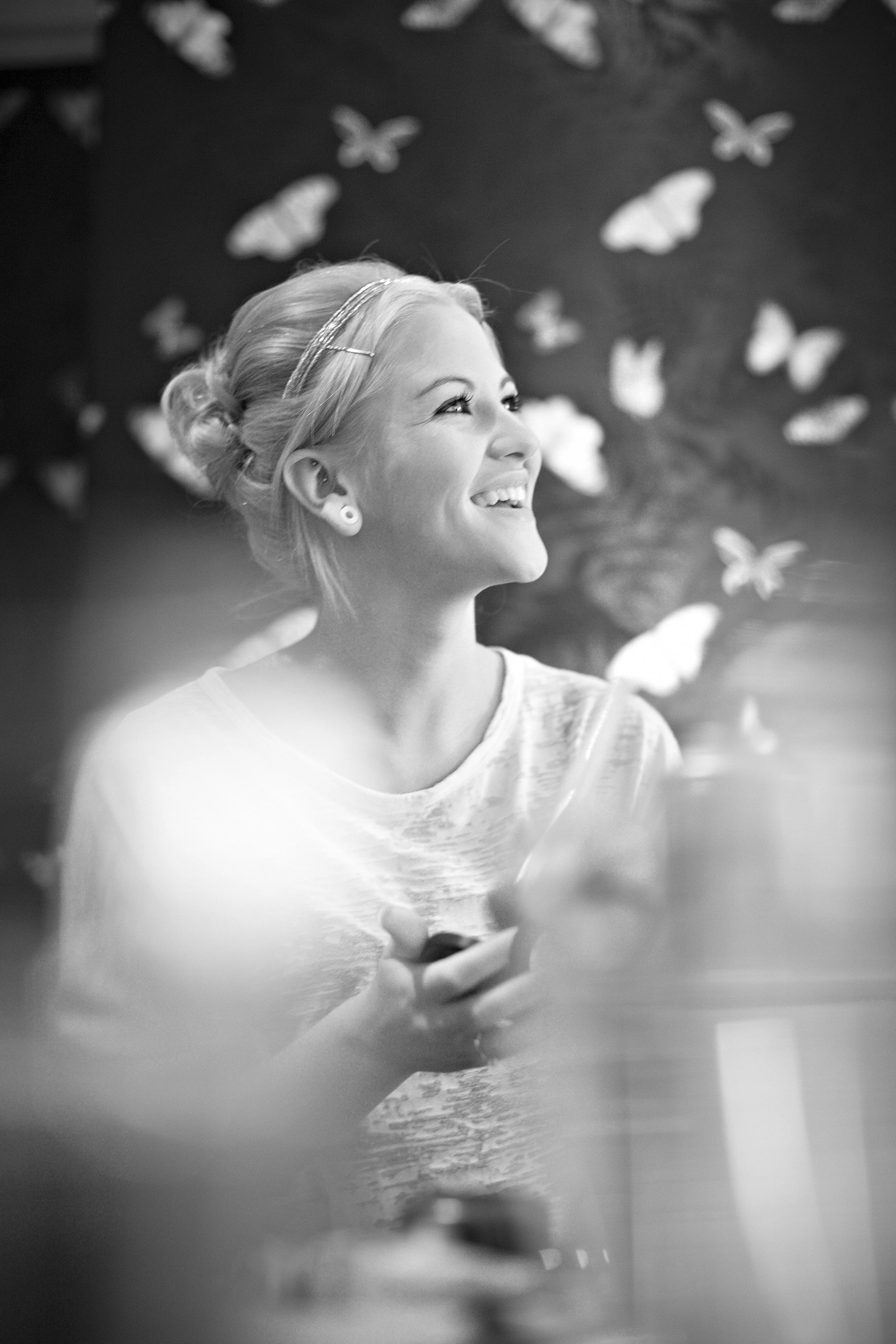 A smiling woman with blonde hair and a headband, looking to the side, surrounded by butterflies.