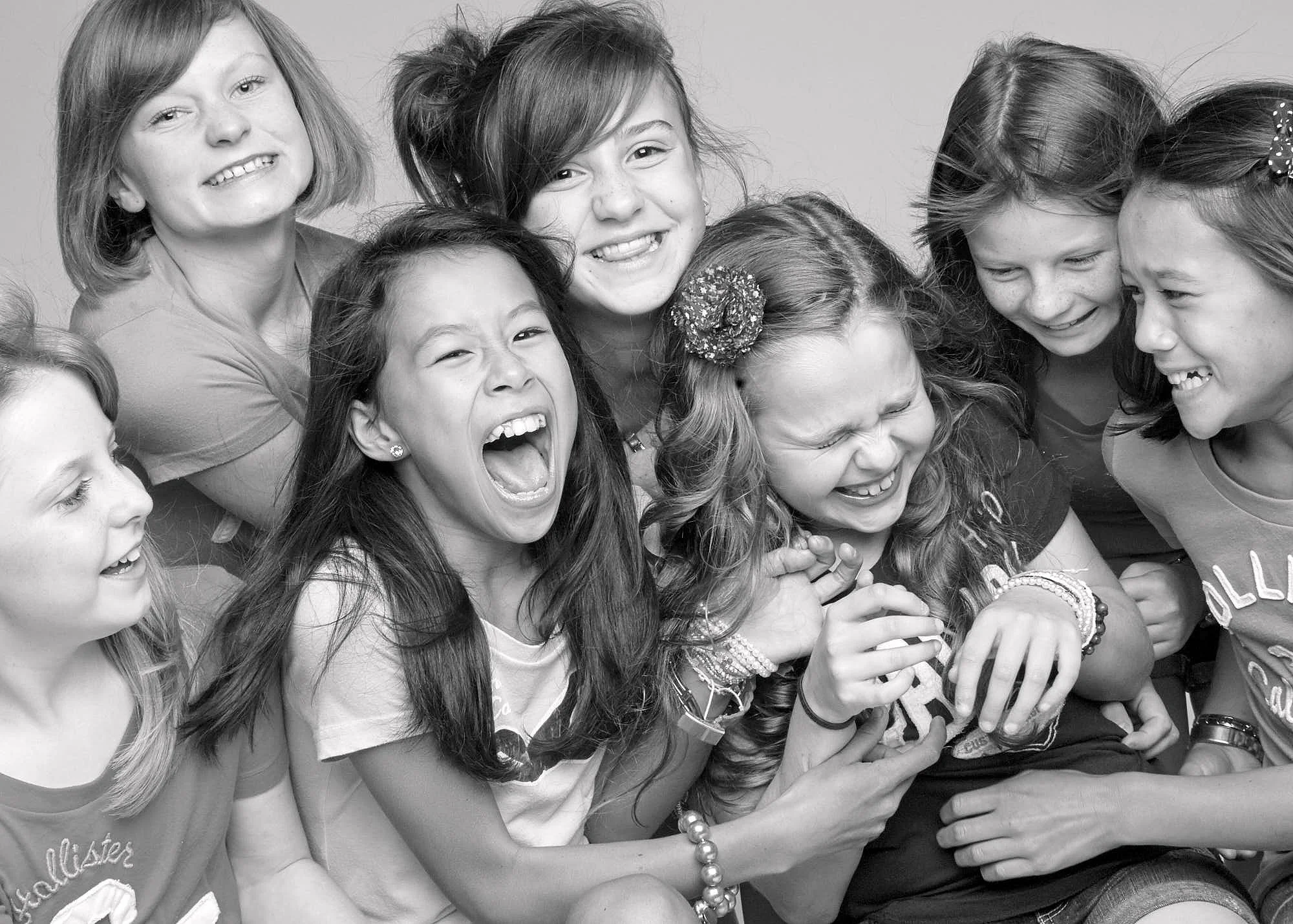 Group of smiling and laughing young girls together in a black and white photo.