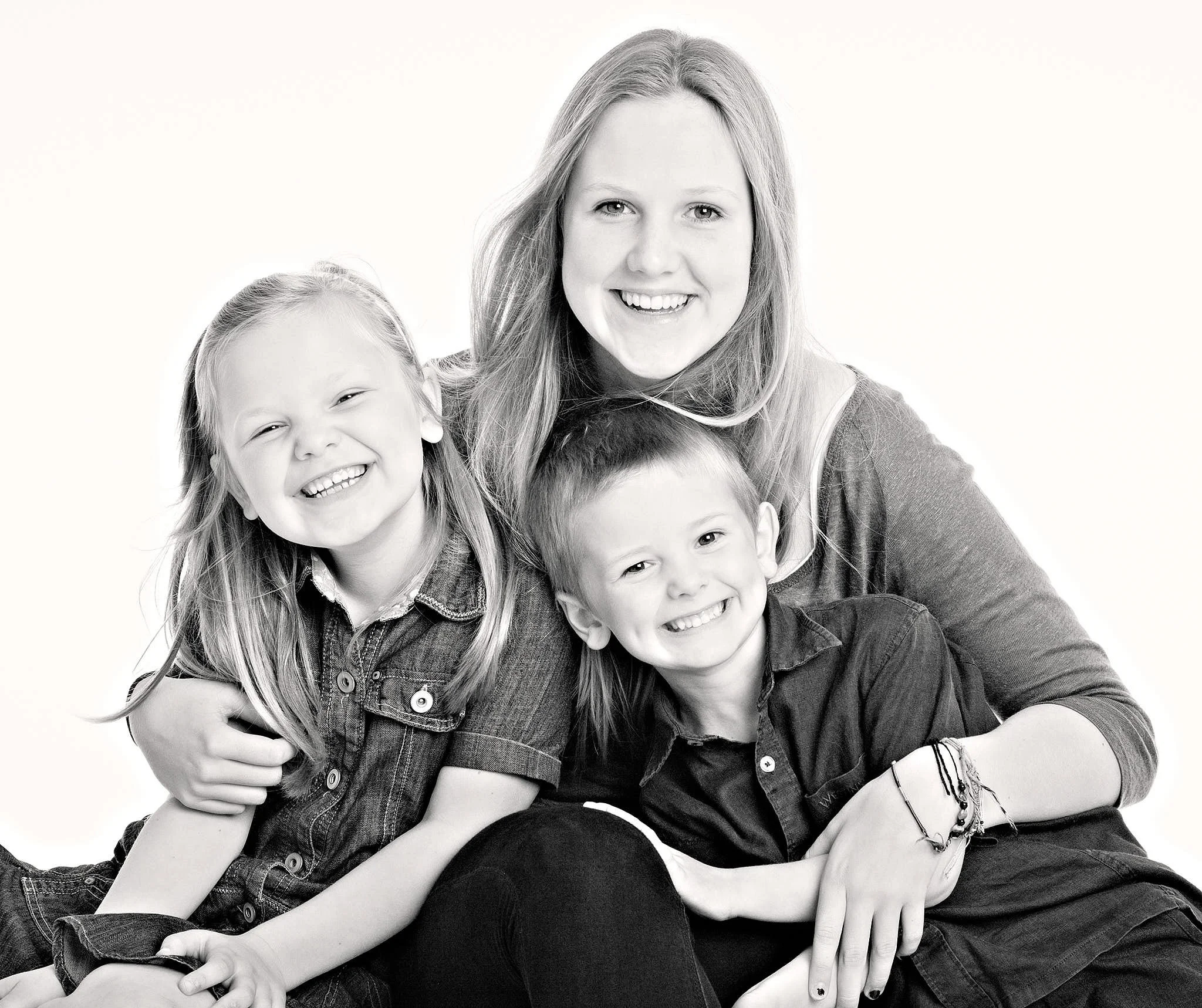 Black-and-white photo of four children smiling and embracing each other closely.