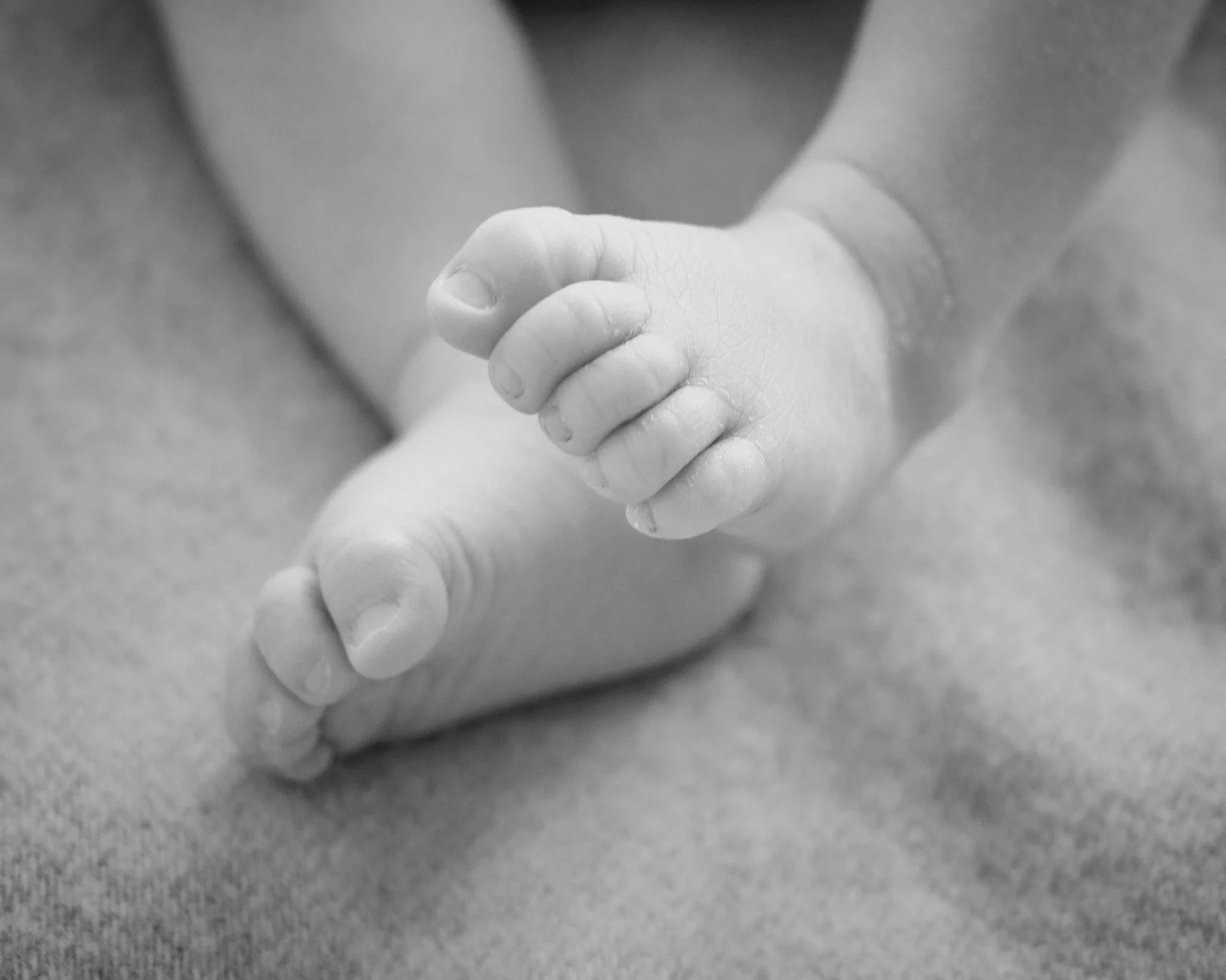A close-up black-and-white photo of an adult holding a baby's hand.