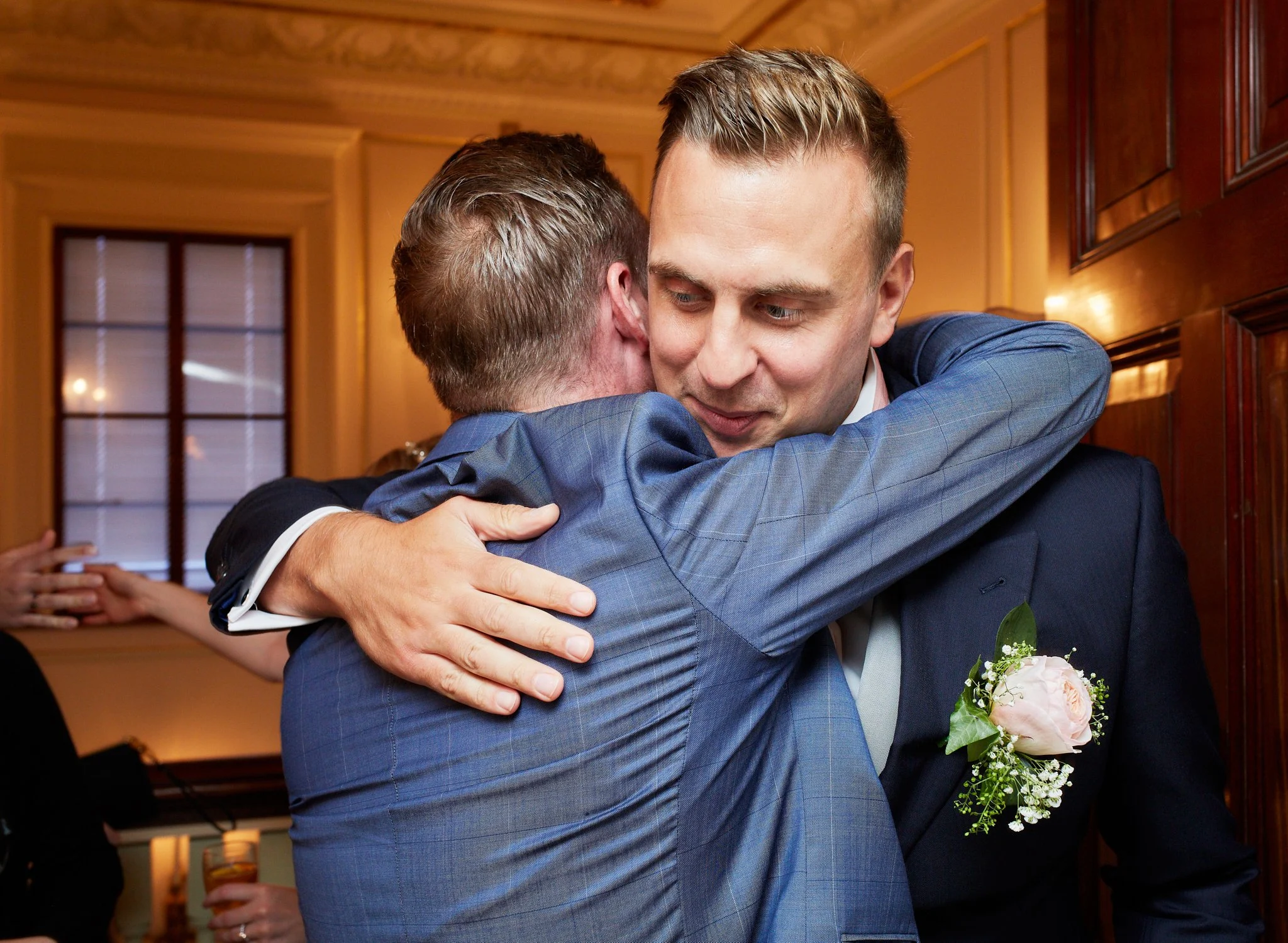 Two men in suits are hugging each other at a formal event.