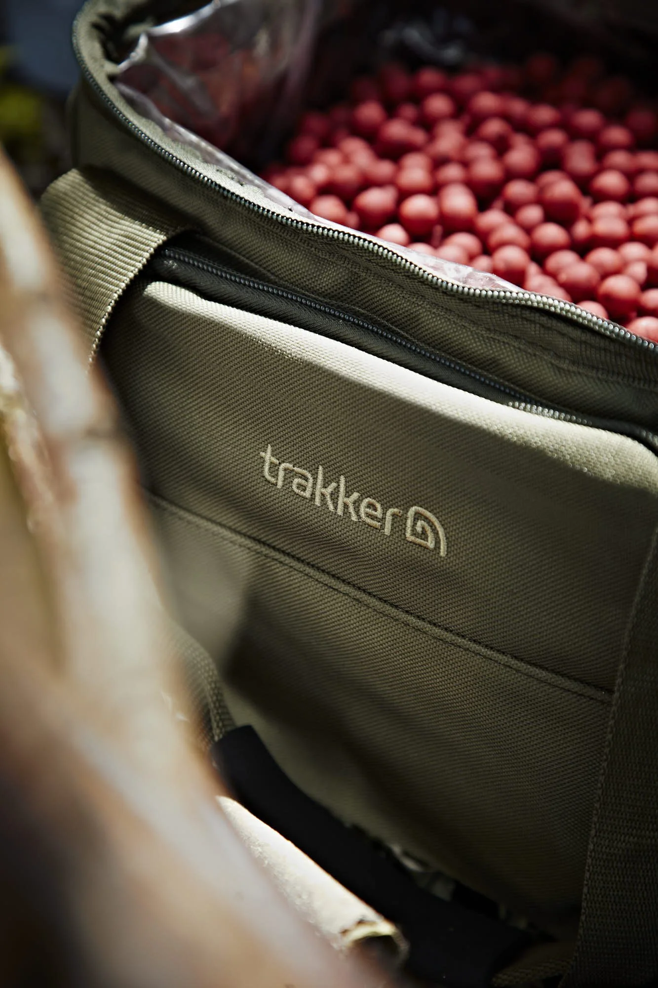 Inside of a beige backpack with the brand name 'trakker' visible, revealing red food or snack items.