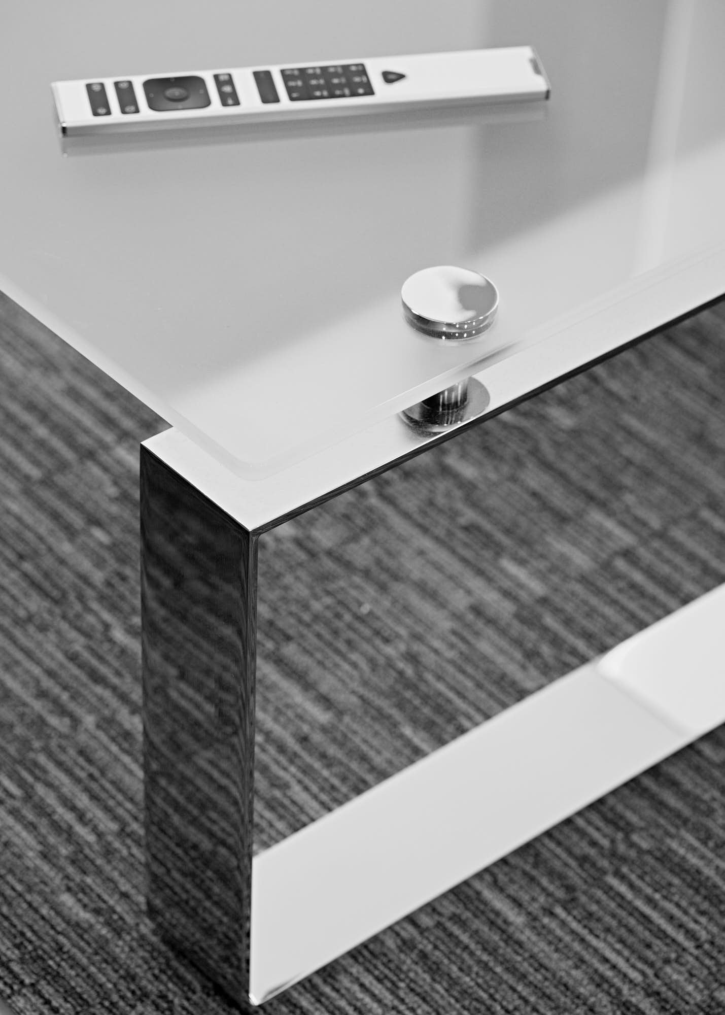 Close-up of a metallic table leg with a small dish on top, on a textured carpeted floor.