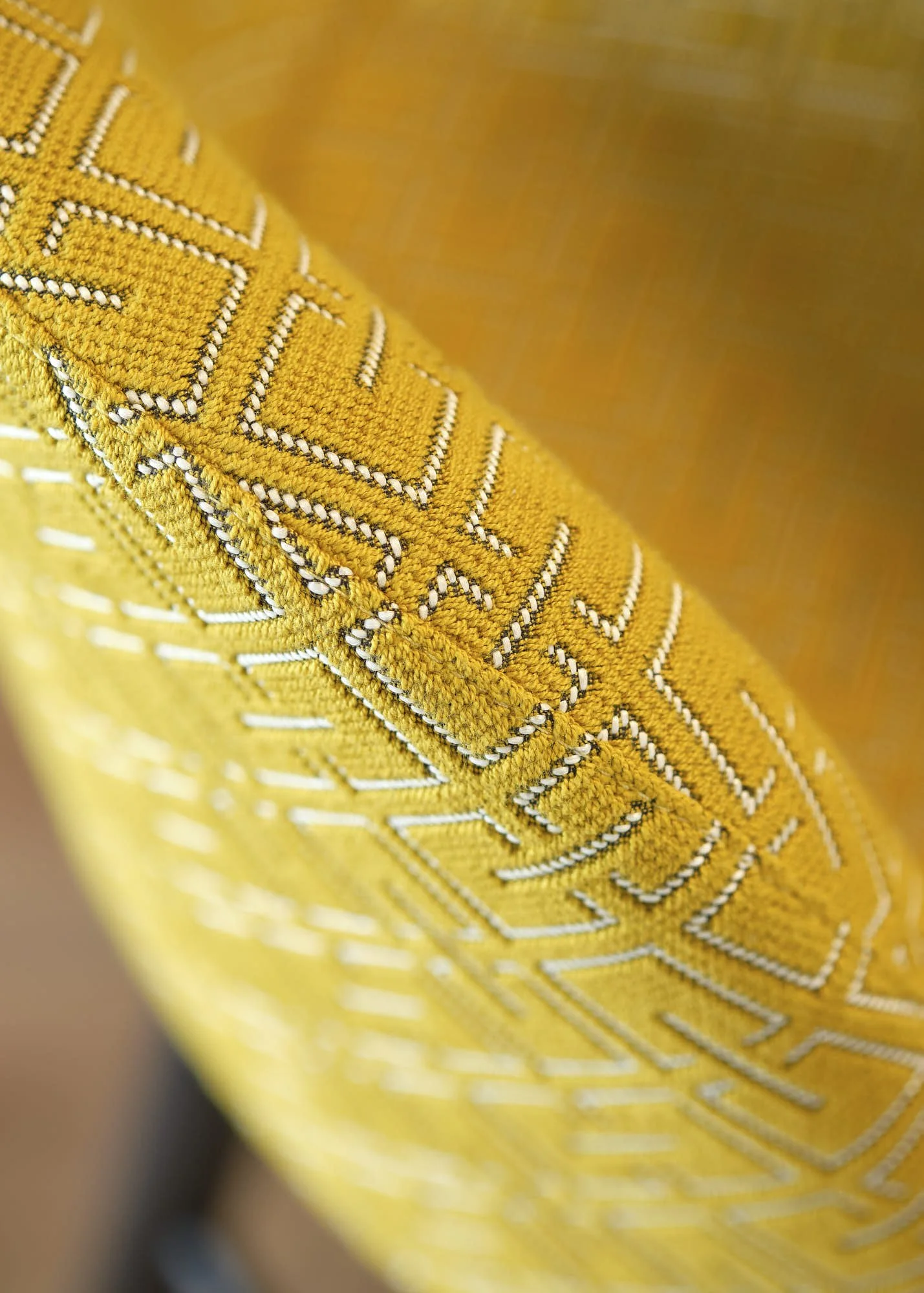 Close-up of a yellow embroidered fabric with white and black detailing, possibly part of a decorative textile or accessory.
