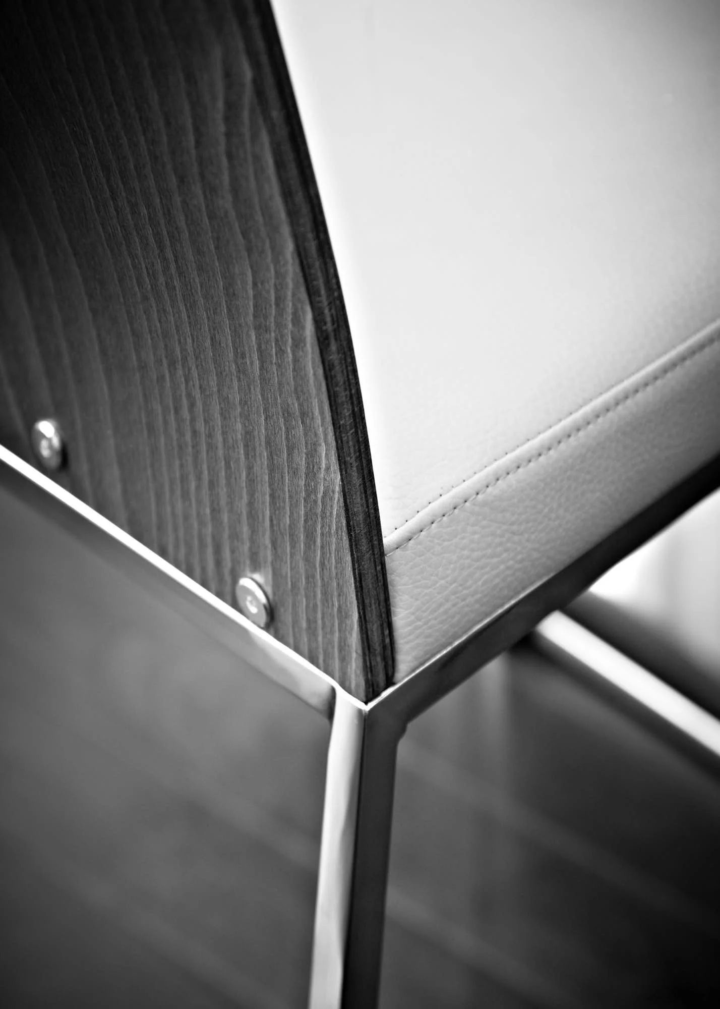 Close-up of a modern table or stand with a wooden surface, metal frame, and bolt details in black and white.