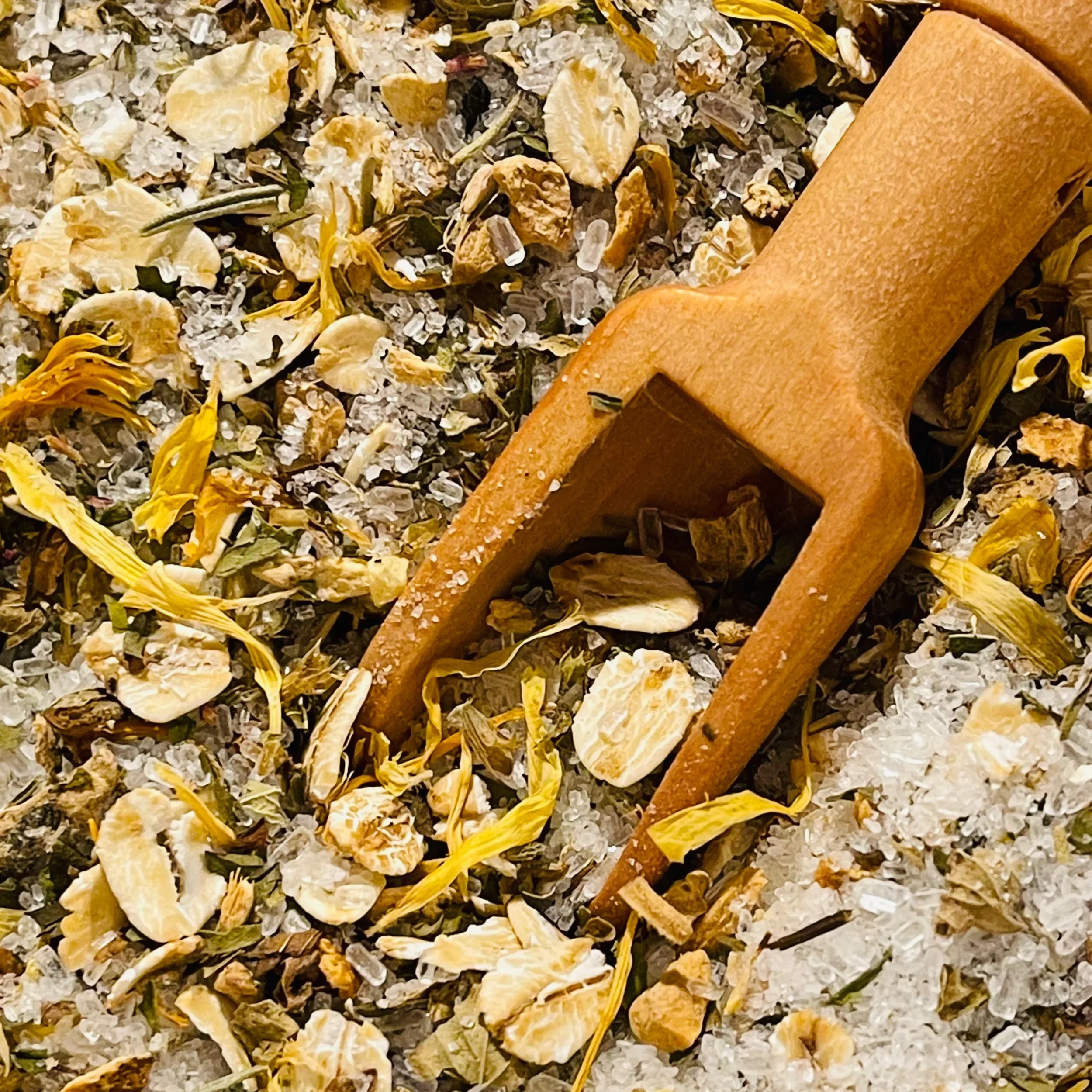 Close-up of a mixture of dried herbs and spices, including turmeric and possibly dried lemon peel, with a cinnamon stick placed on top.