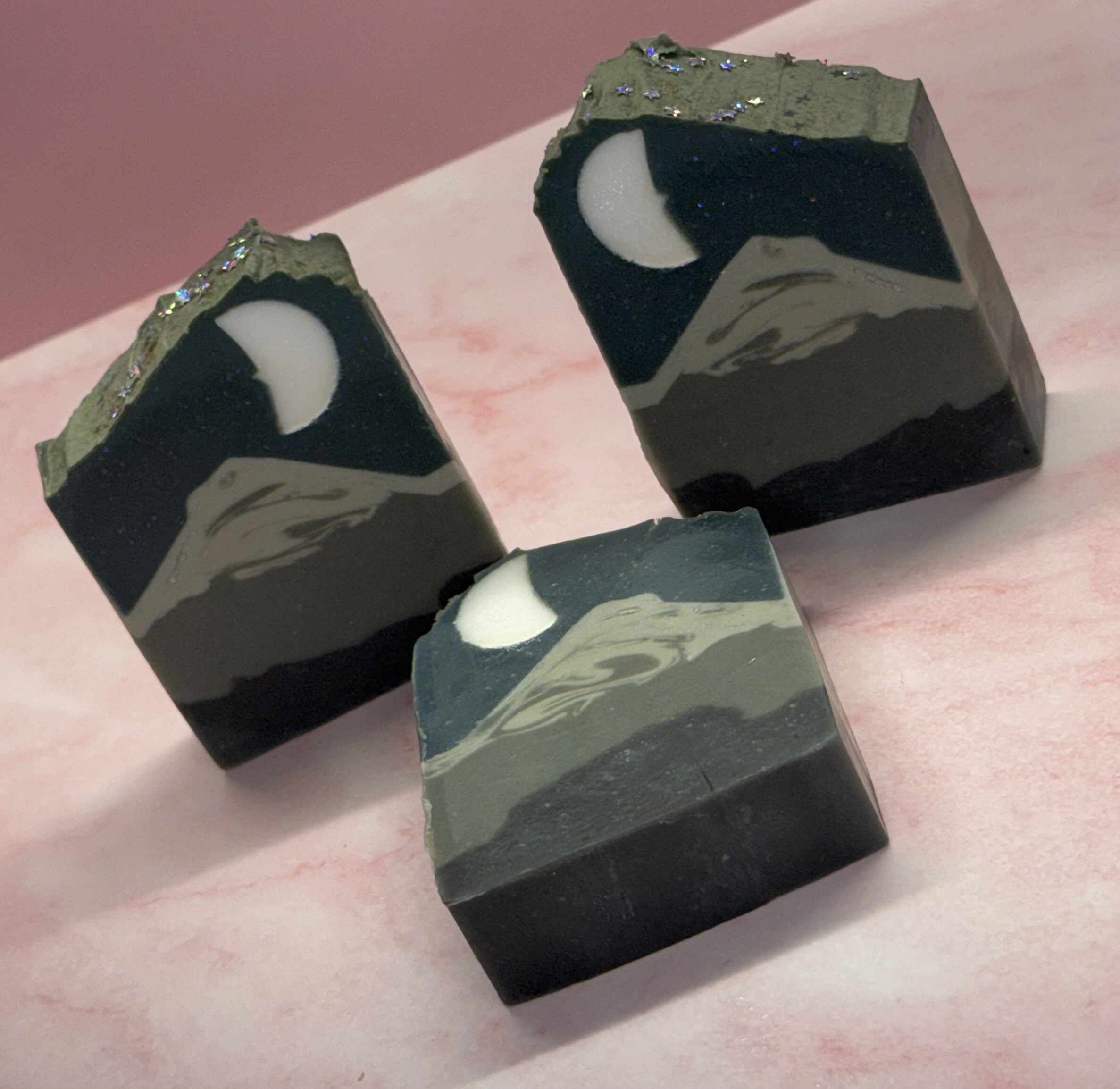 Close-up of two rectangular bars of soap, one with a black and white yin-yang symbol, on a pink surface.