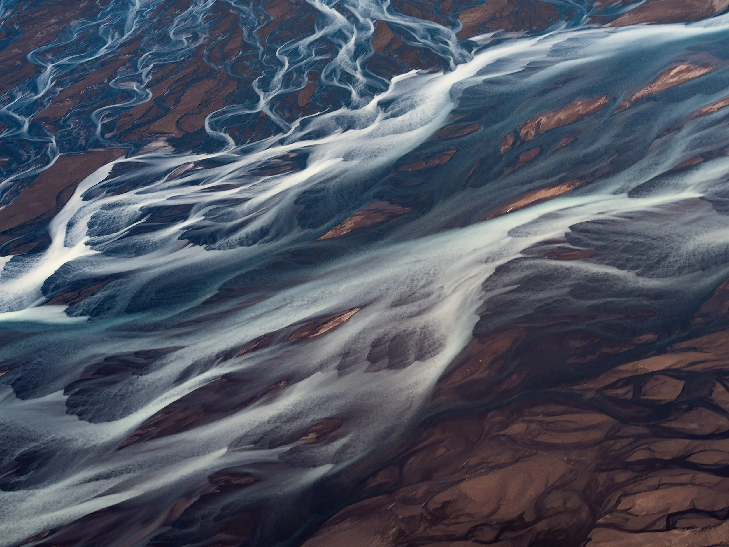 Aerial view of a braided river delta, channels of water flowing through the land.