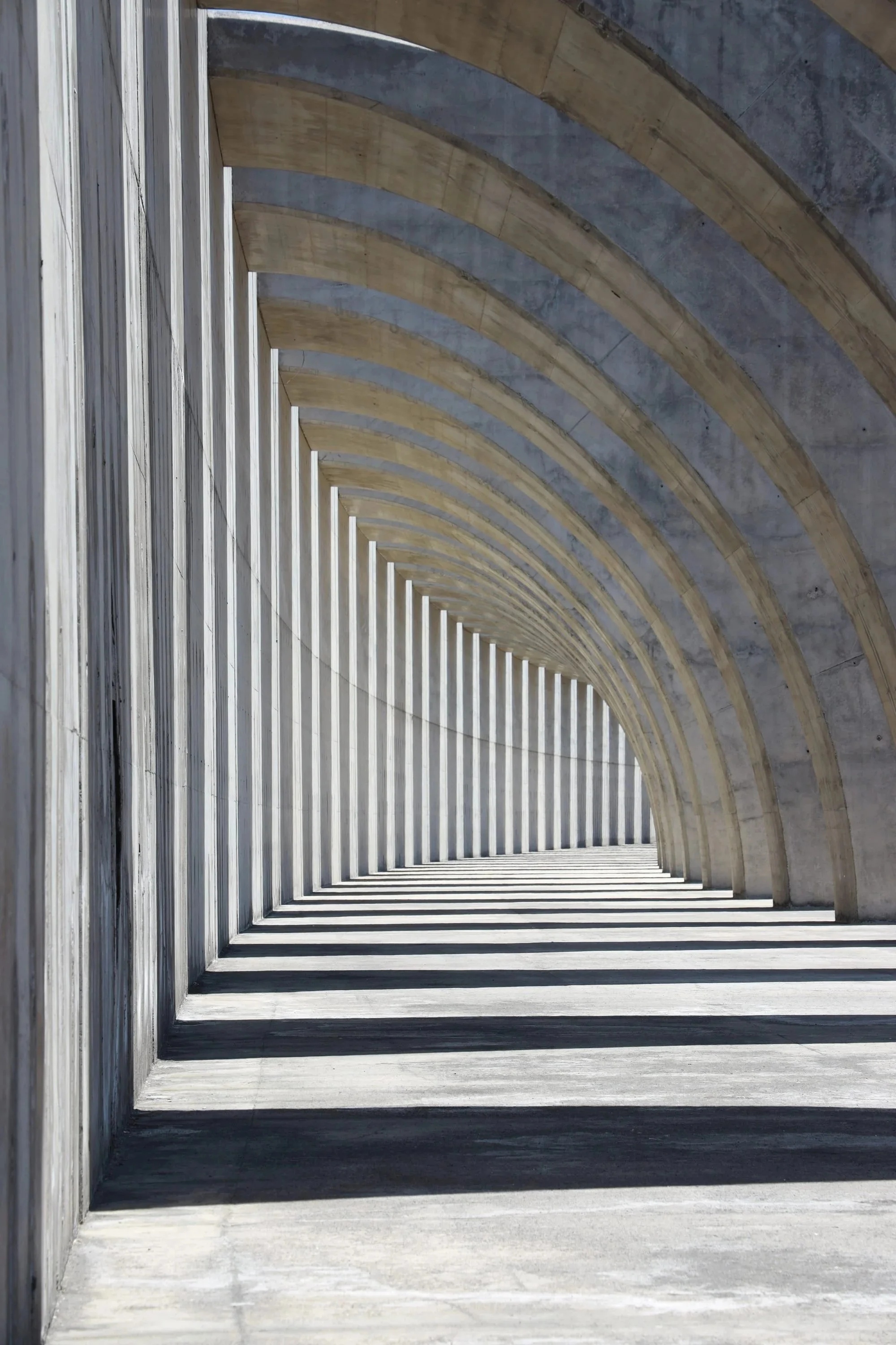 A colonnade of concrete arches receding into the distance.