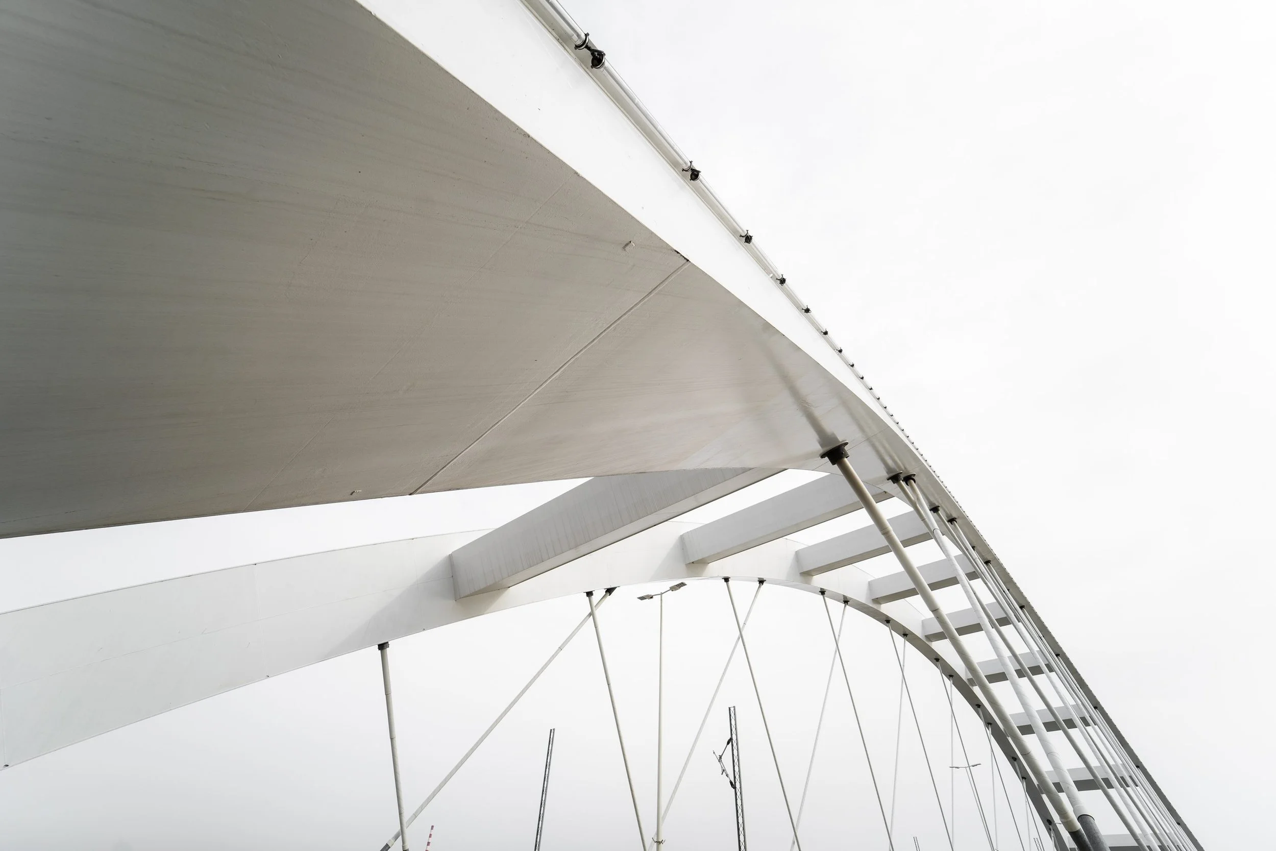 Underside of an arched bridge structure with steel cables, suggesting connection.