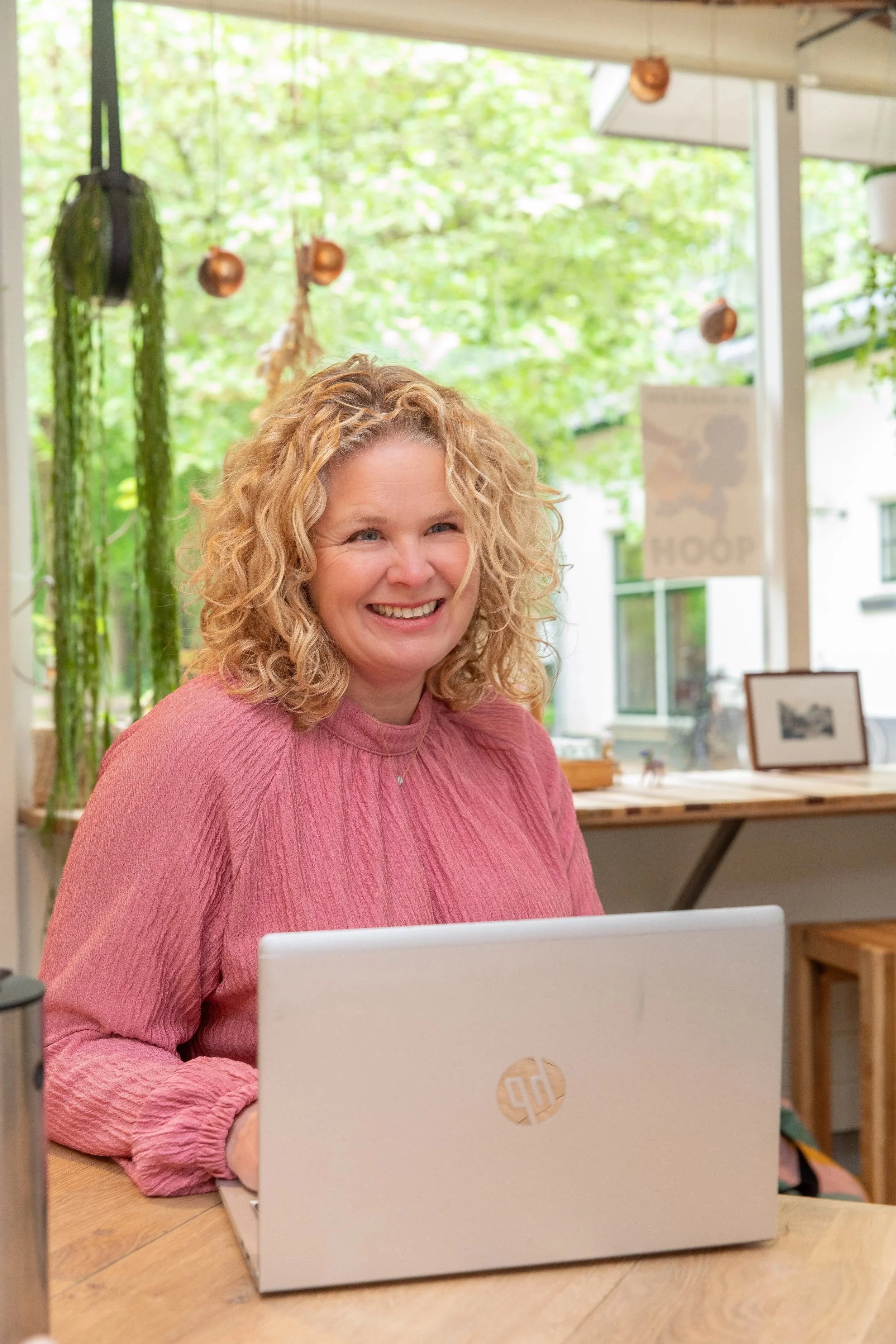 Joëla van Dantzig achter laptop kijkt de klant lachend aan