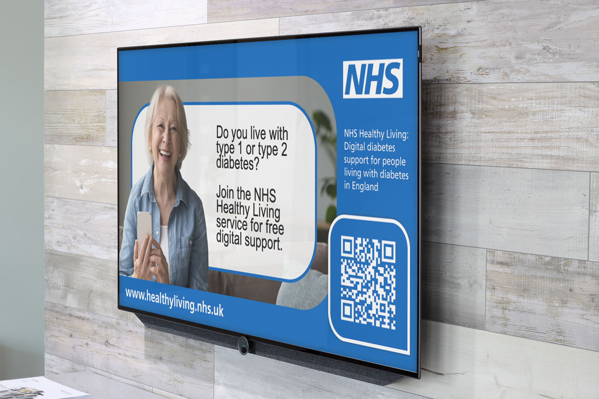 A digital screen mounted on a wall displaying NHS Healthy Living information about support for people living with diabetes, with a QR code and website link.