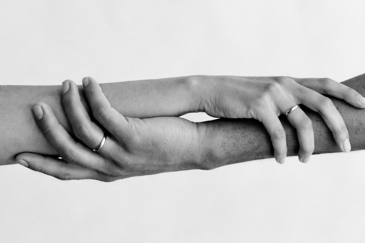 Bride and groom holding hands wearing bespoke wedding bands and a diamond engagement ring. Black and white wedding photography celebrating marriage, commitment union and handcrafted bridal jewellery. Quiet Luxury Style.