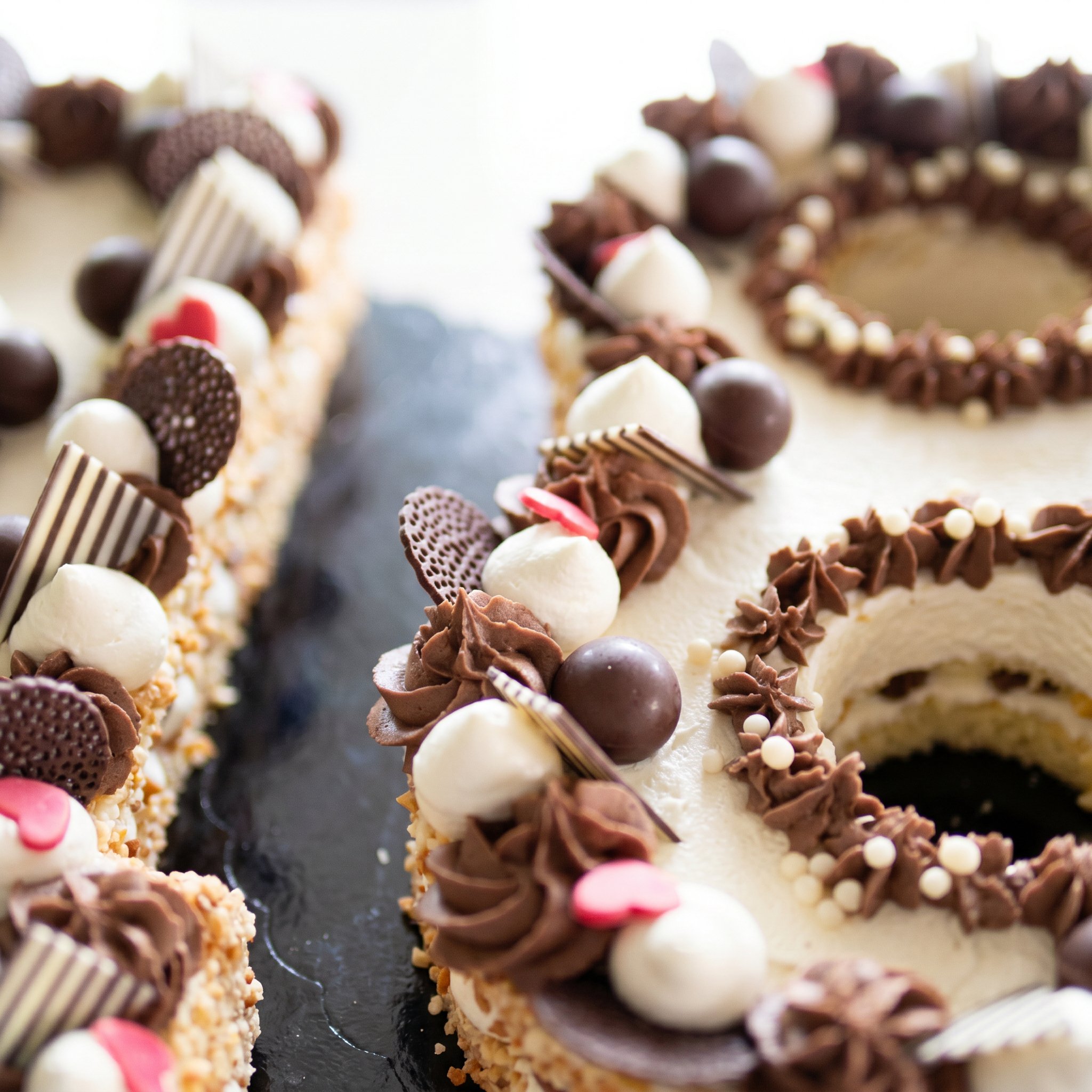 Torte decorate con cioccolato, cioccolatini, panna e cuori di zucchero