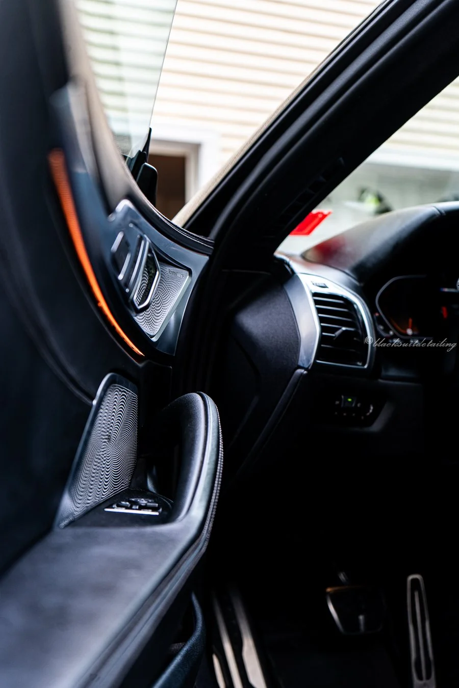 Inside a vehicle showing the dashboard, air vents, and a side control panel with a speaker and window controls.