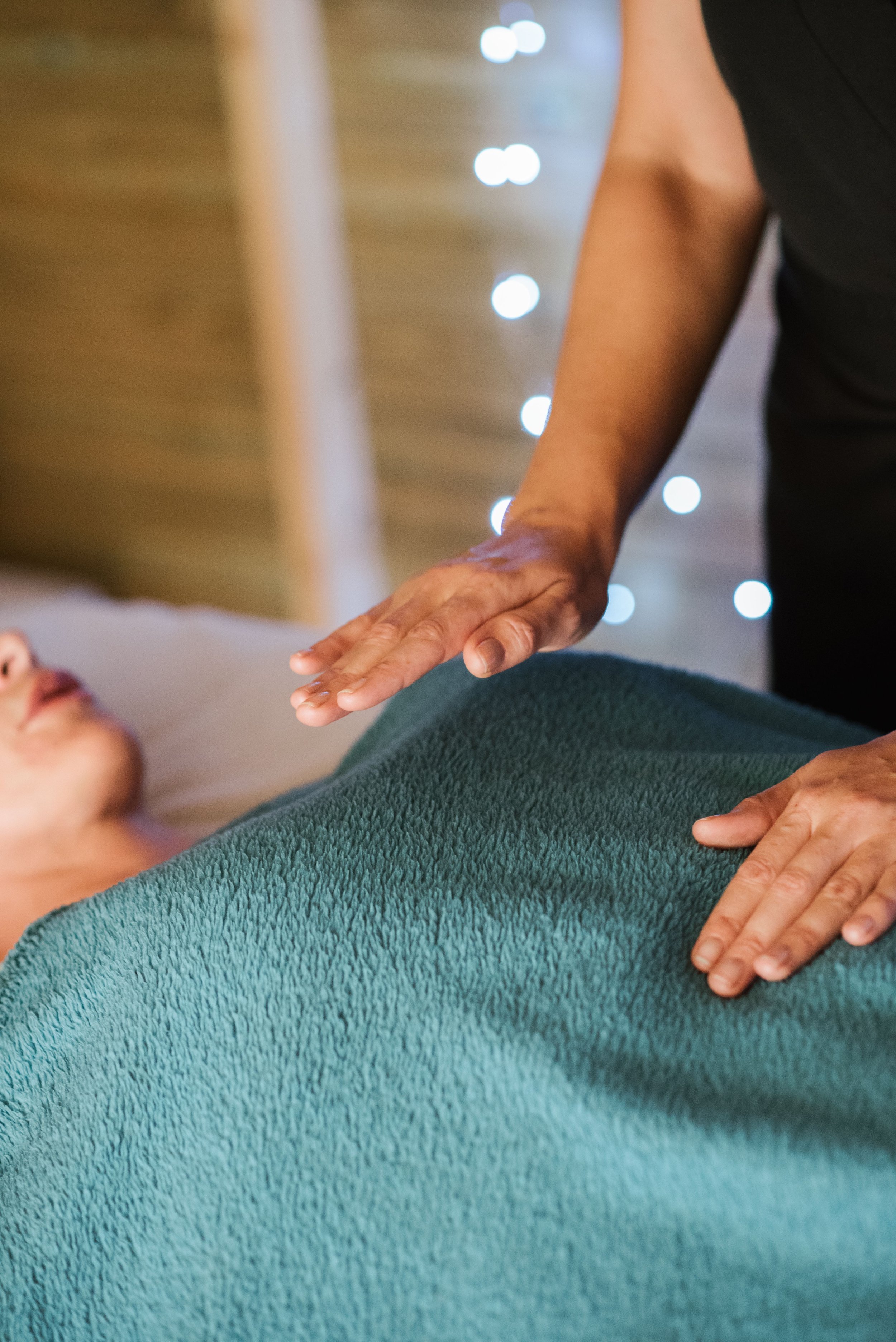 A person is giving a massage to a woman lying on a bed, with a focus on the woman's face and the person's hands.