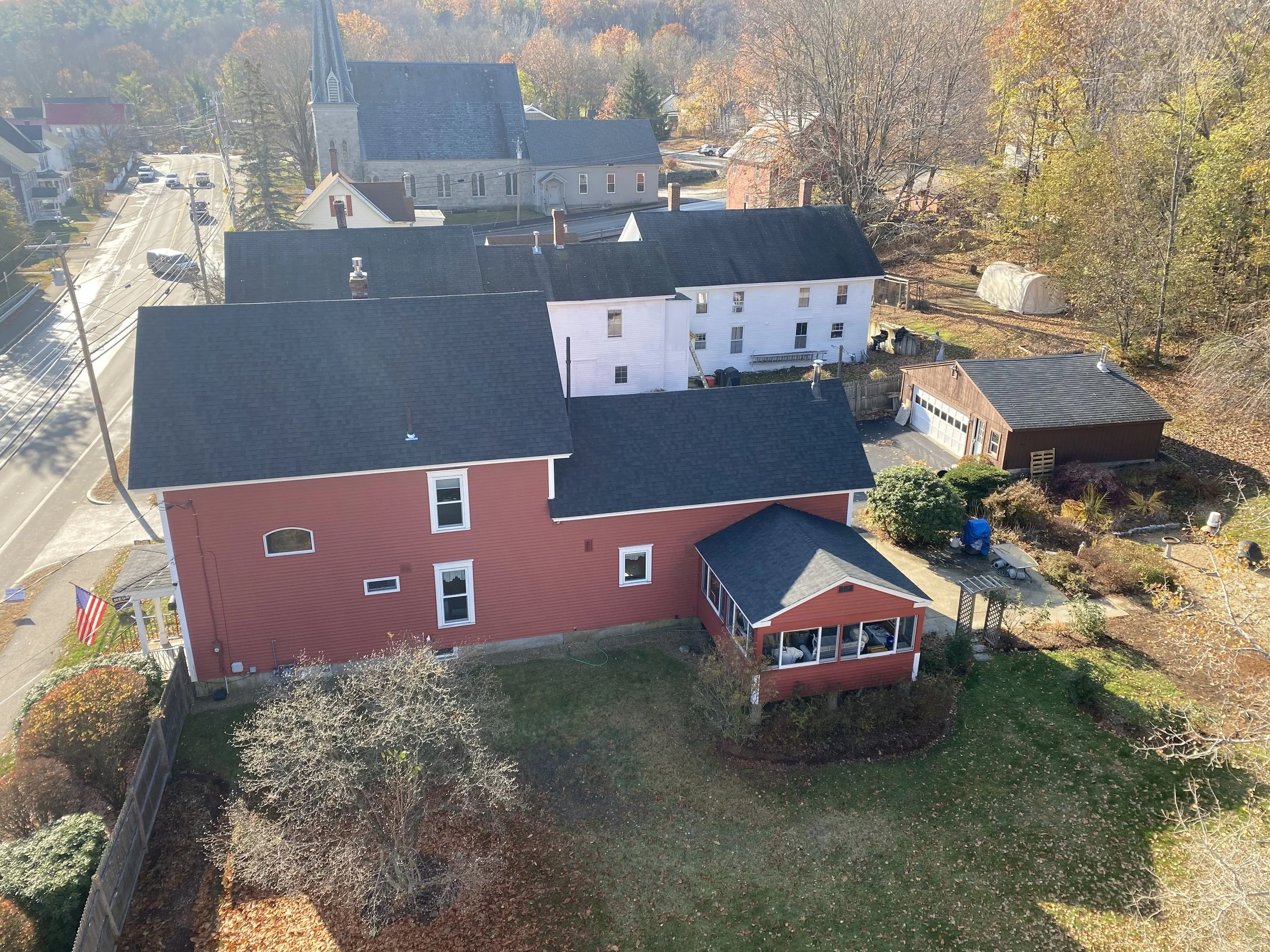 Aerial view of a New England neighborhood showcasing residential homes with durable roofing and a historic church.