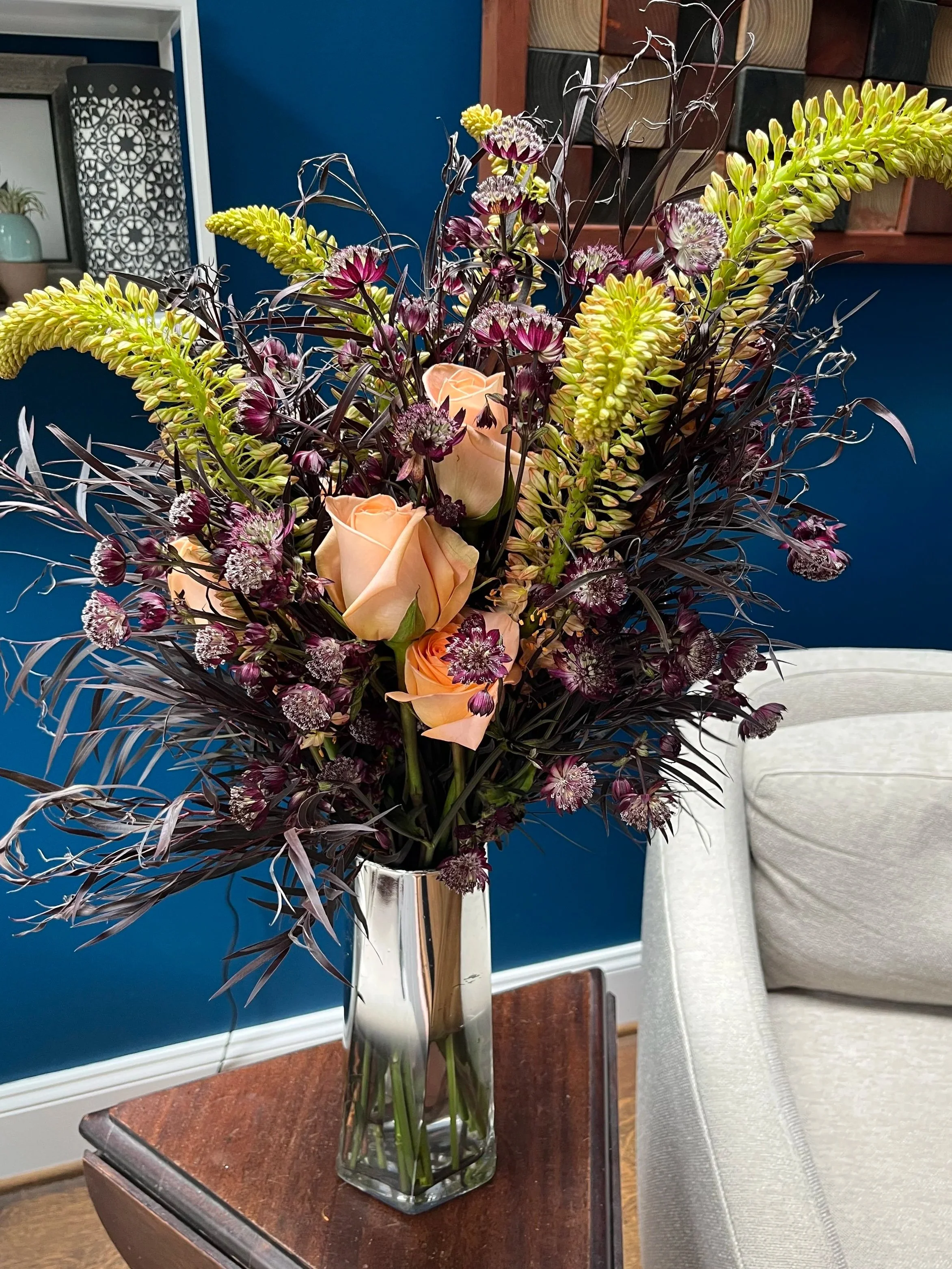A bouquet of peach roses rising out of dark purple leaves.