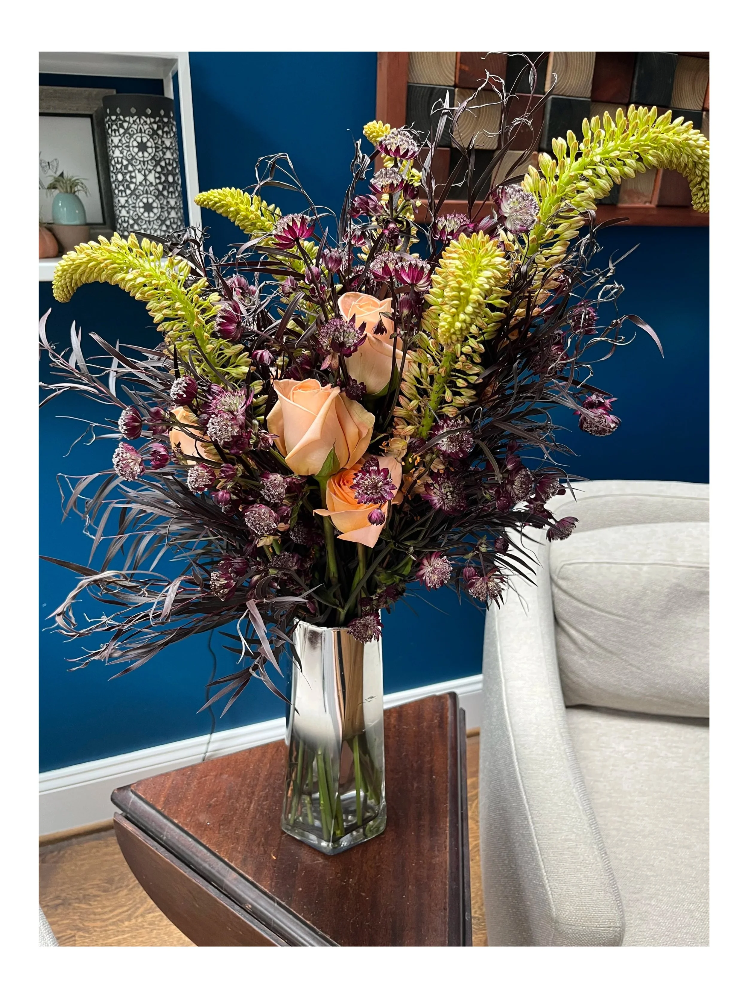 Haunting floral arrangement in modern, mirrored vase.