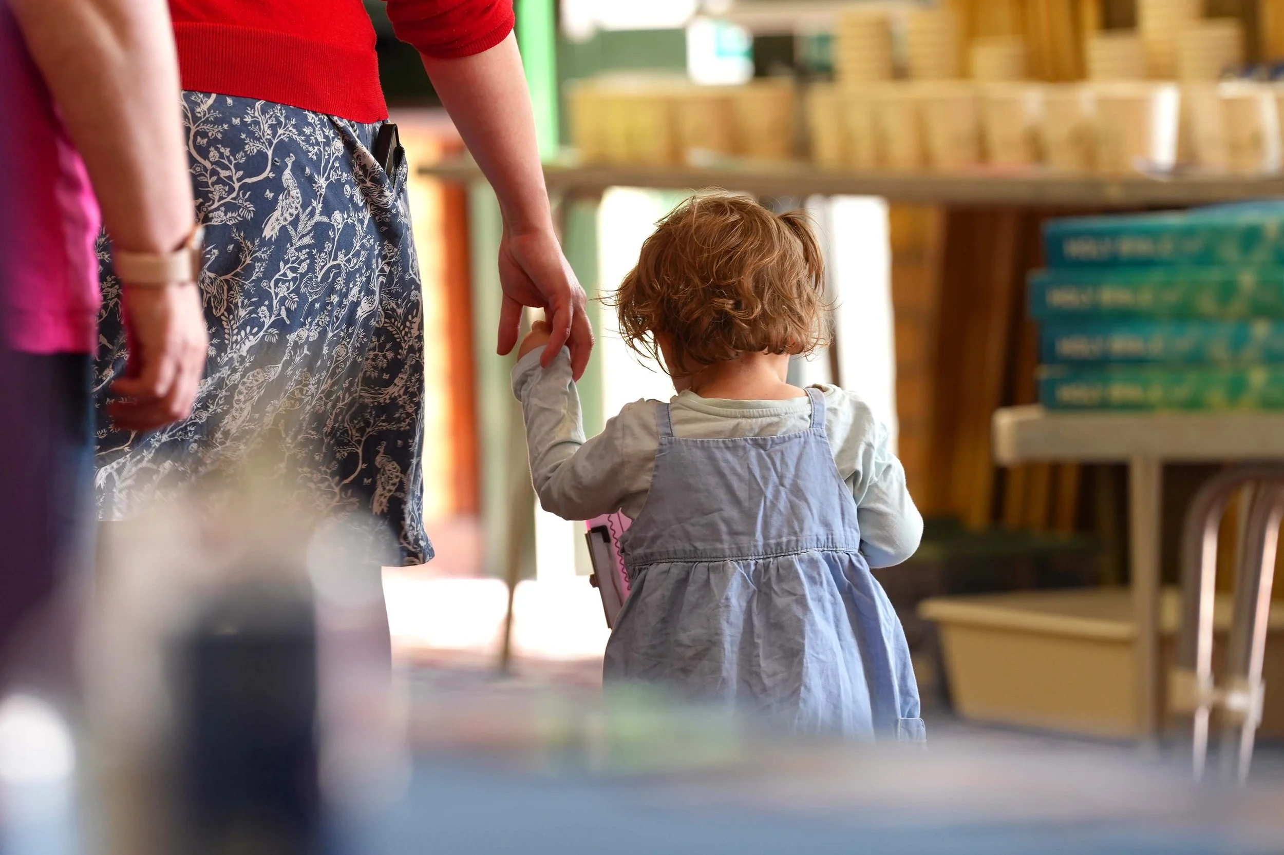 A young girl with curly hair holding the hand of an adult during a Sunday Service at Grace.