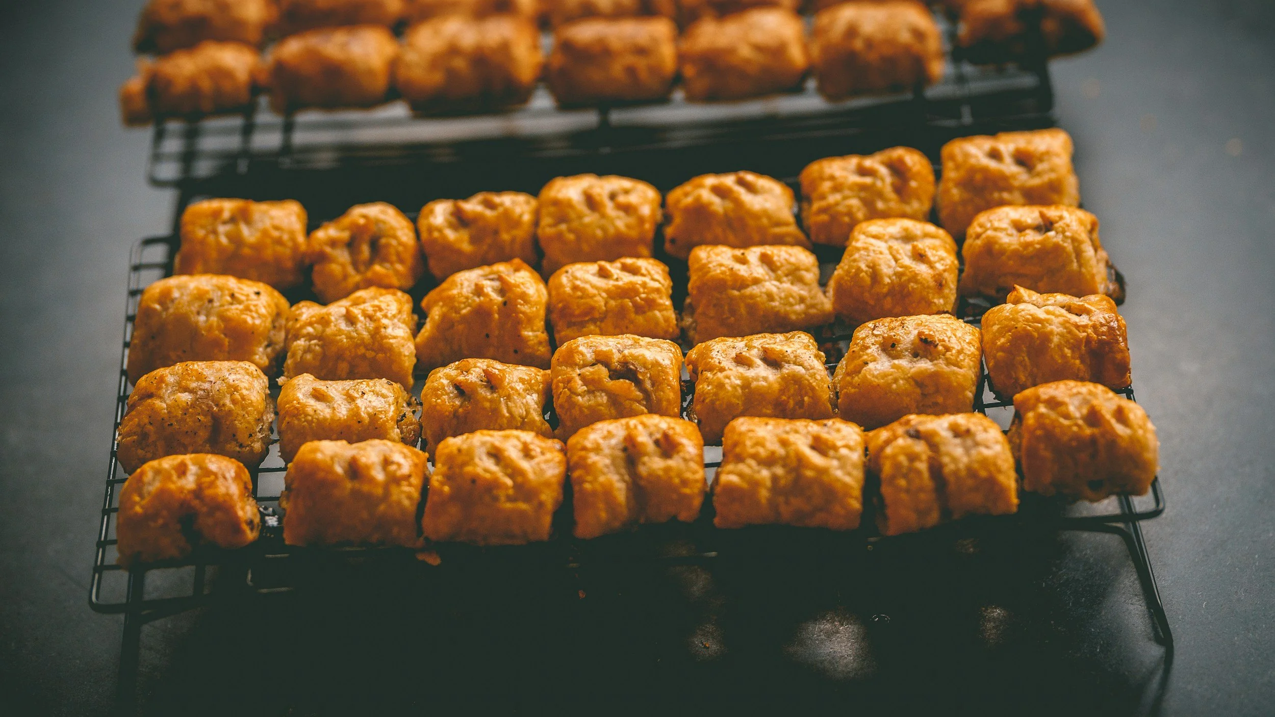 Close-up of golden-brown cornbread muffins cooling on a black wire rack.