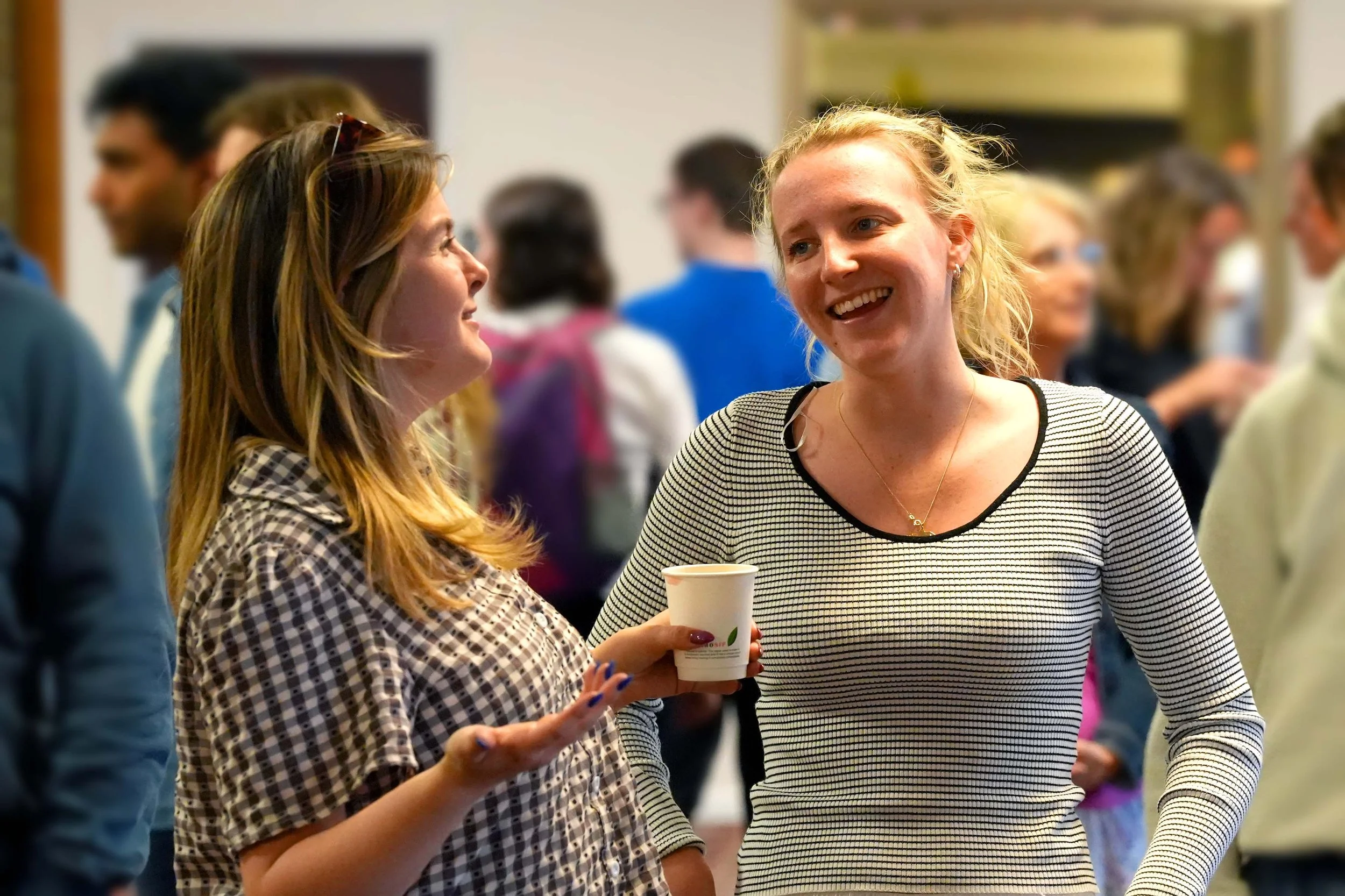 Two young women are smiling and engaged in conversation after a Sunday Service at Grace Community Church, Bedford.