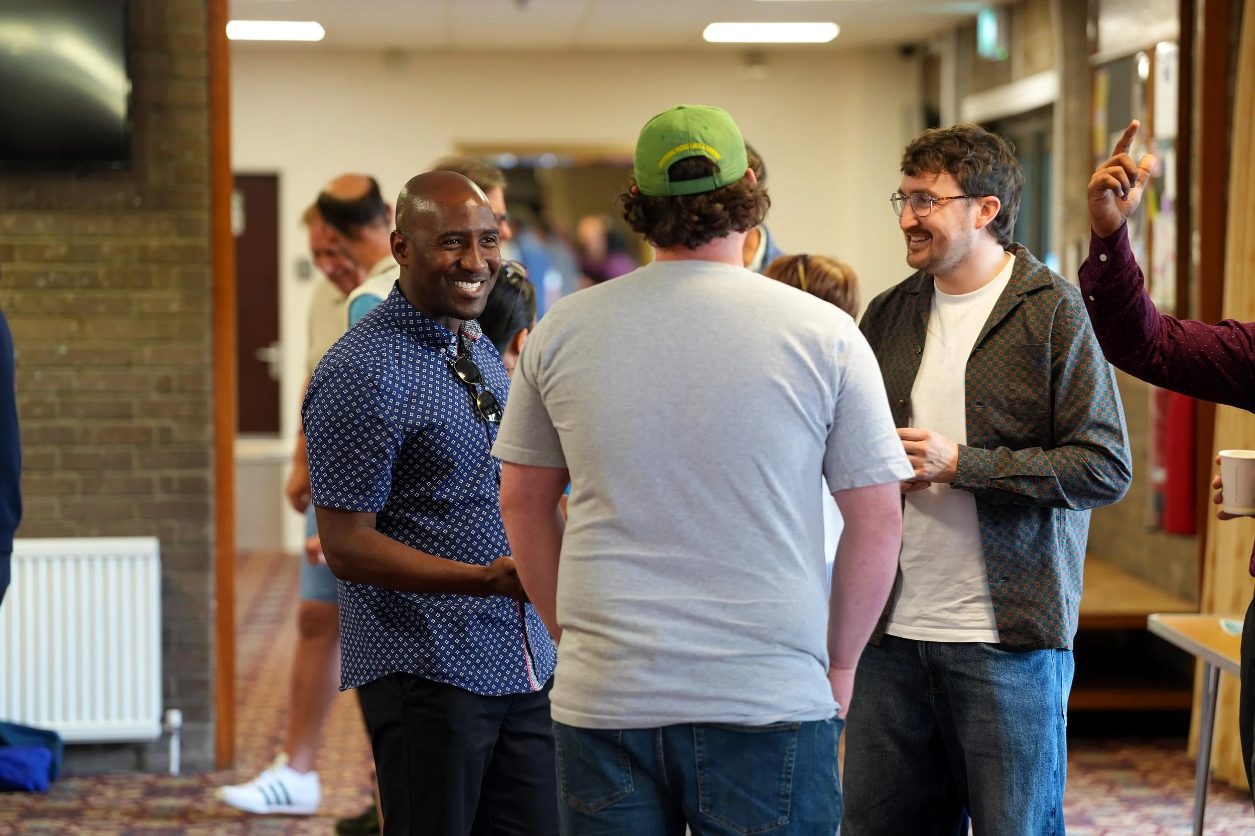 Group of four diverse men engaging in a conversation over a coffee after a Sunday Service at Grace.