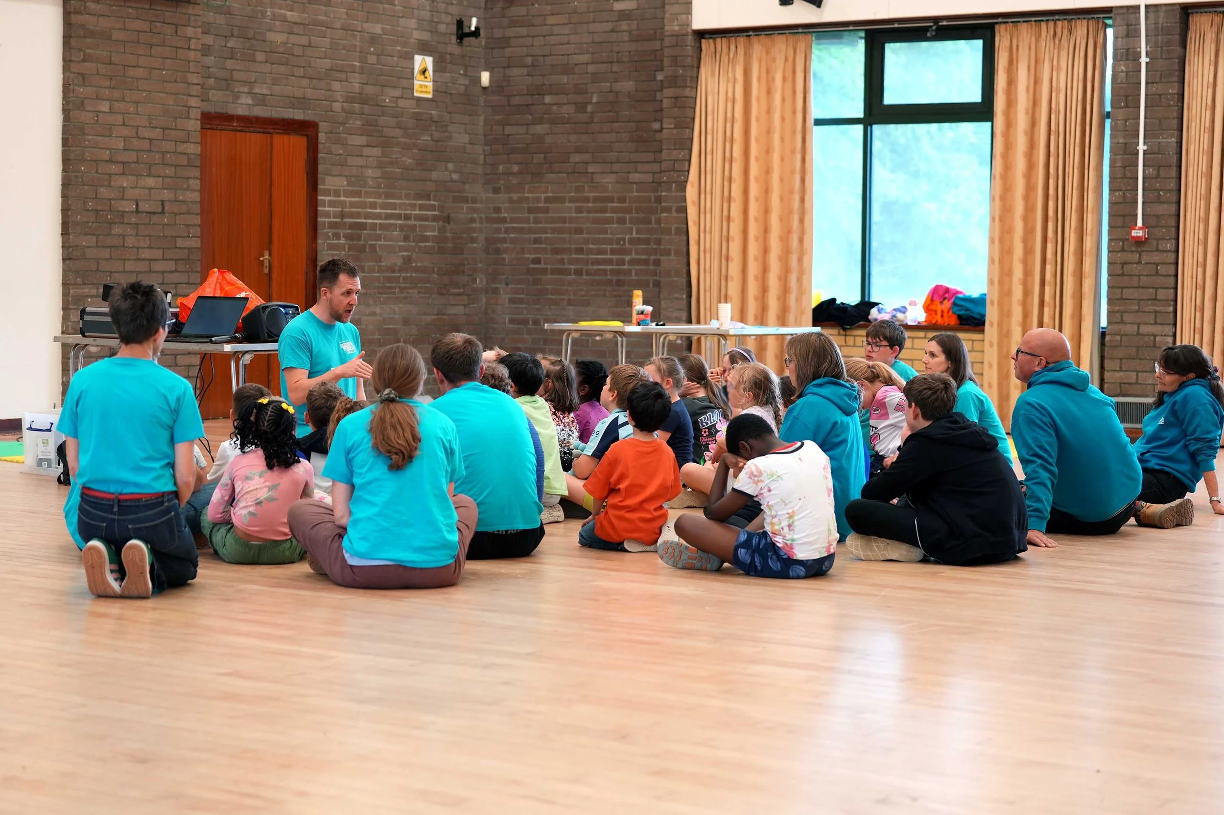 A group of children and adults sitting on the floor listening to a story at one of Grace's many kids clubs that take place during the week in Kempston. #Youth #Children #KidsClubs