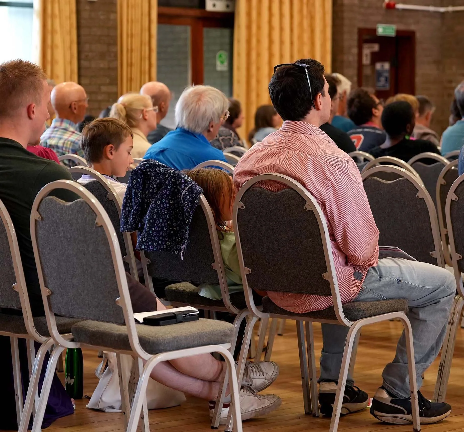 Congregation of diverse people, including children, adults, and seniors, seated in chairs during a Sunday Service at Grace Community Church, Bedford.