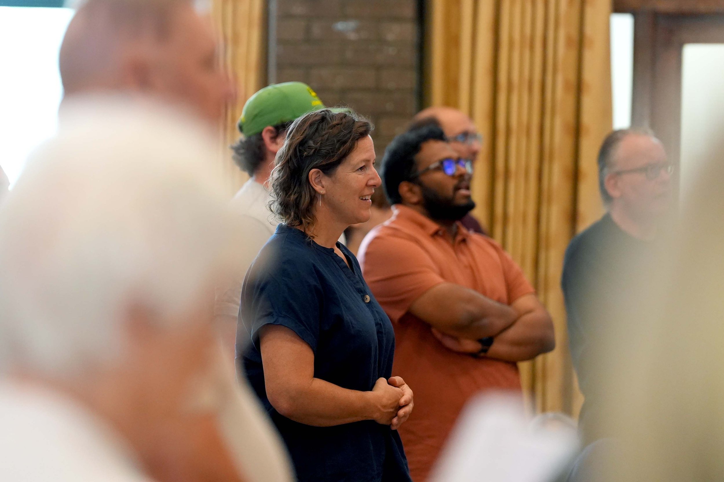 Side view of a diverse group of adults standing in a room, during one of our Sunday Services. #Grace #Church #SundayServices