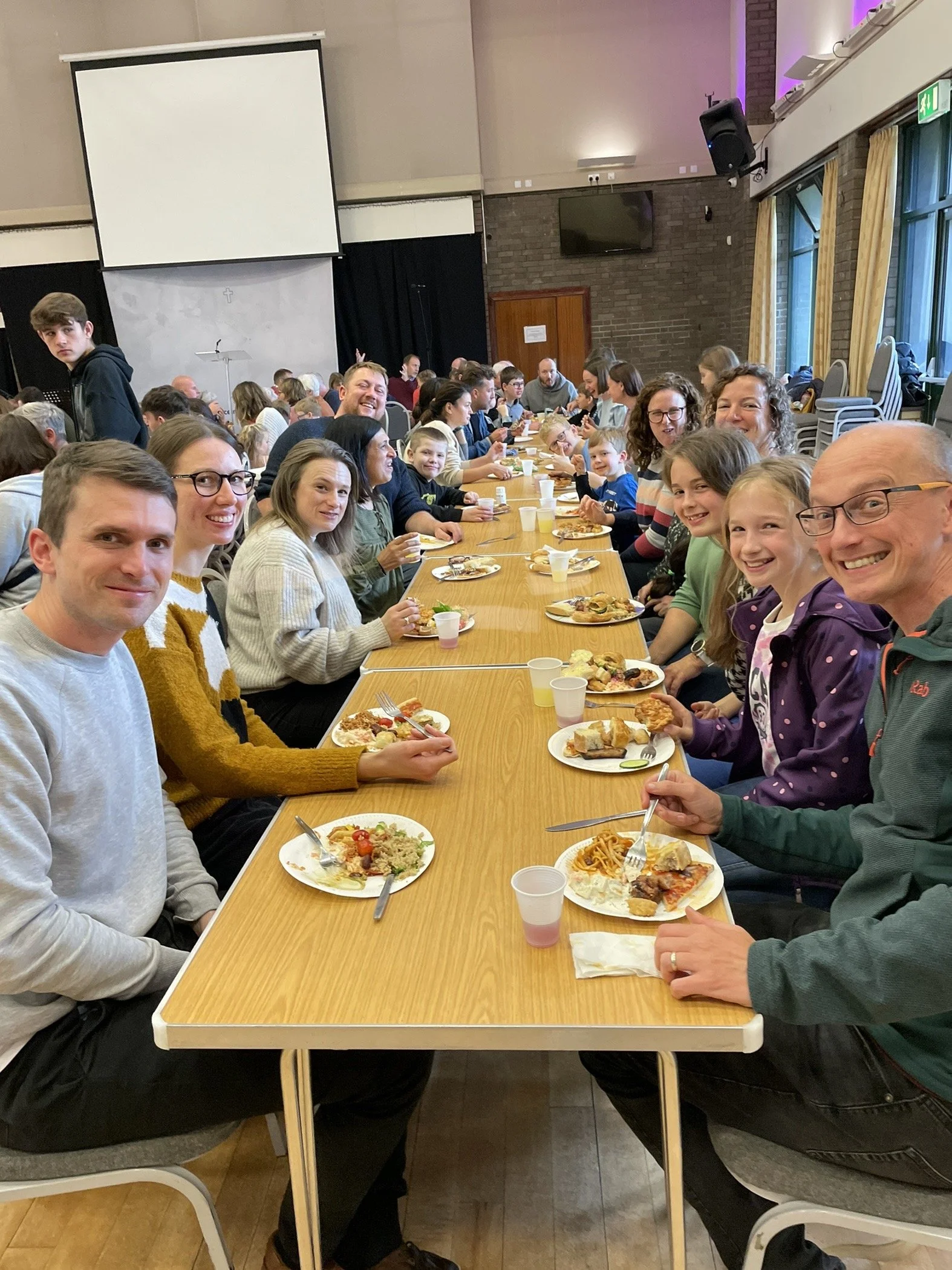 People sitting around a long table enjoying a meal at Grace Community Churches 'Big Sunday Lunch', which takes place each month.