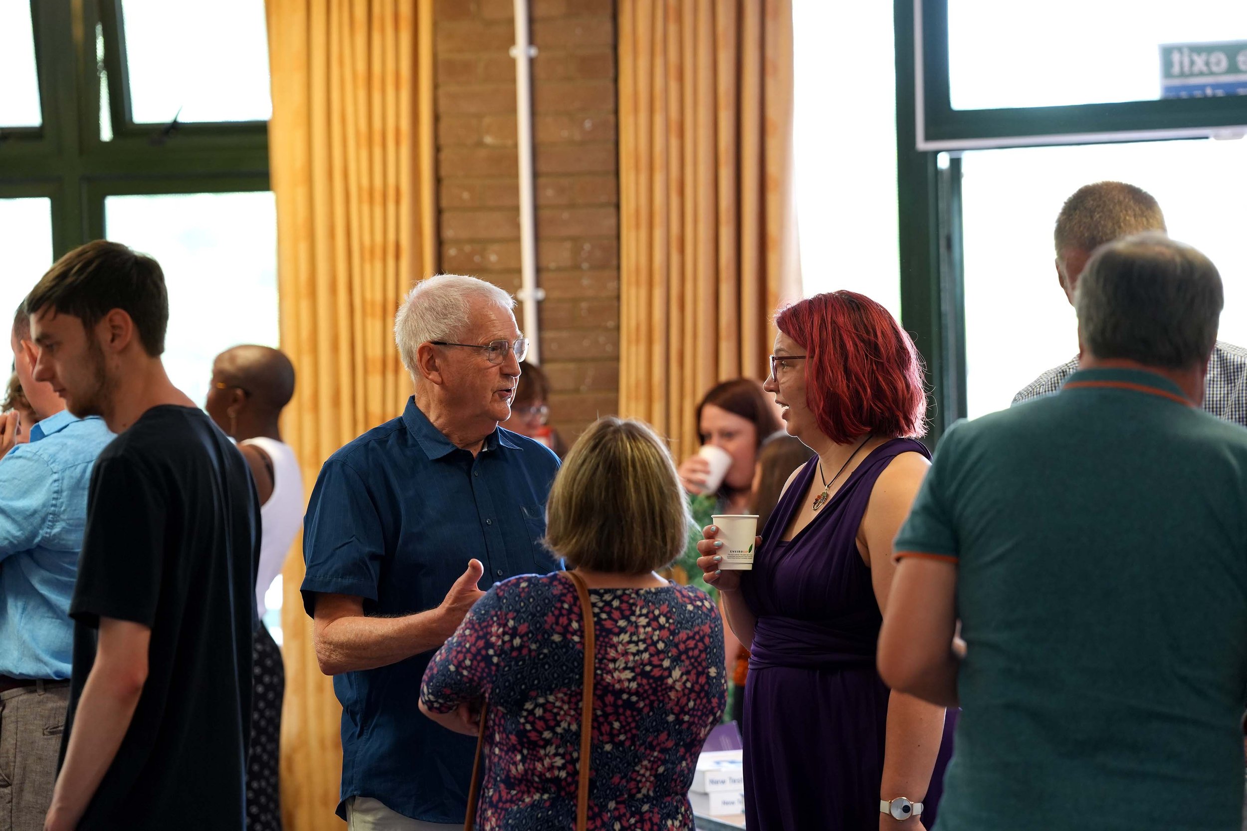 A group of people gathered indoors, engaged in conversation after a Sunday Service at Grace Community Church, Kempston.