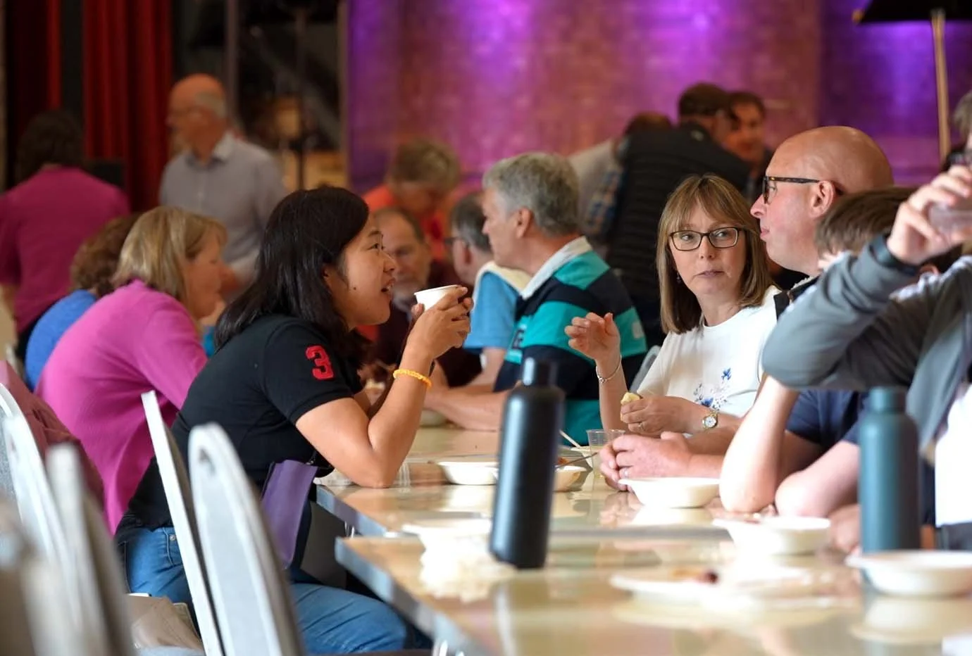 People gathered around a table in a restaurant or dining hall, talking and eating.