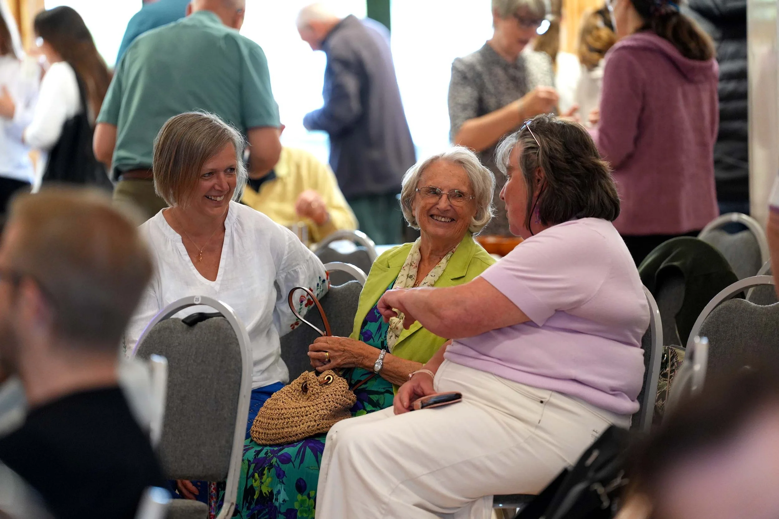 A group of people at a Grace Sunday Service are chatting and smiling. 