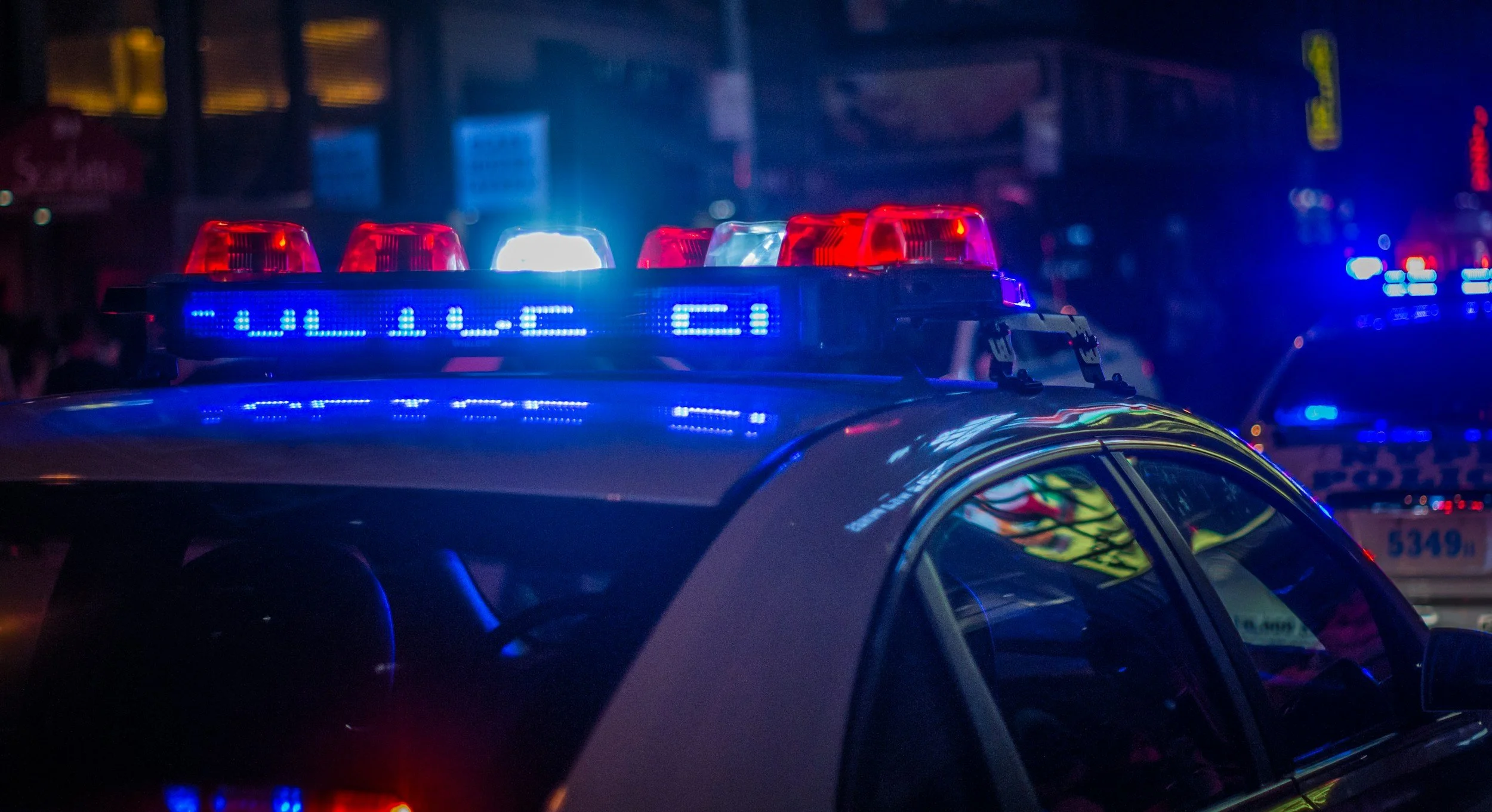 Police car with flashing red and blue emergency lights at night.