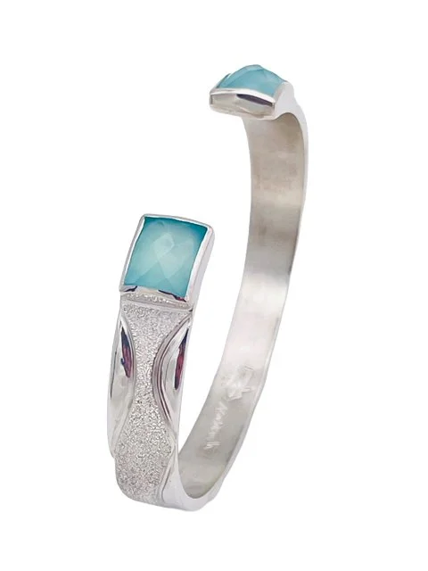 A silver bracelet with a light blue gemstone on each end.