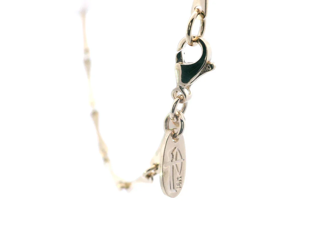 Close-up of a silver chain bracelet with a lobster clasp and a small oval maker's mark.