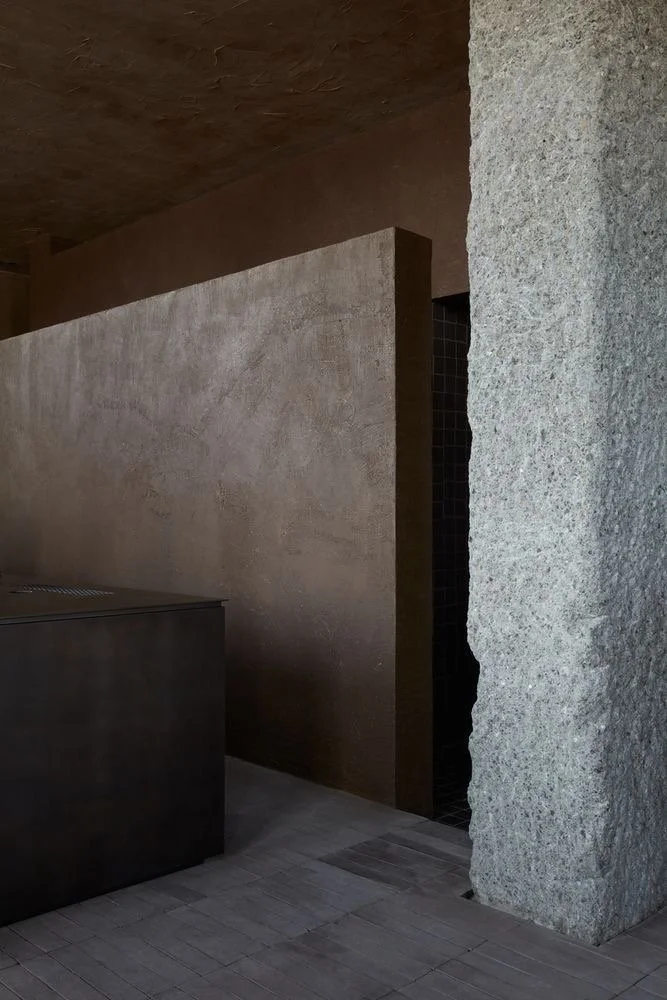 Interno minimalista con pareti di pietra e un divisorio in calcestruzzo