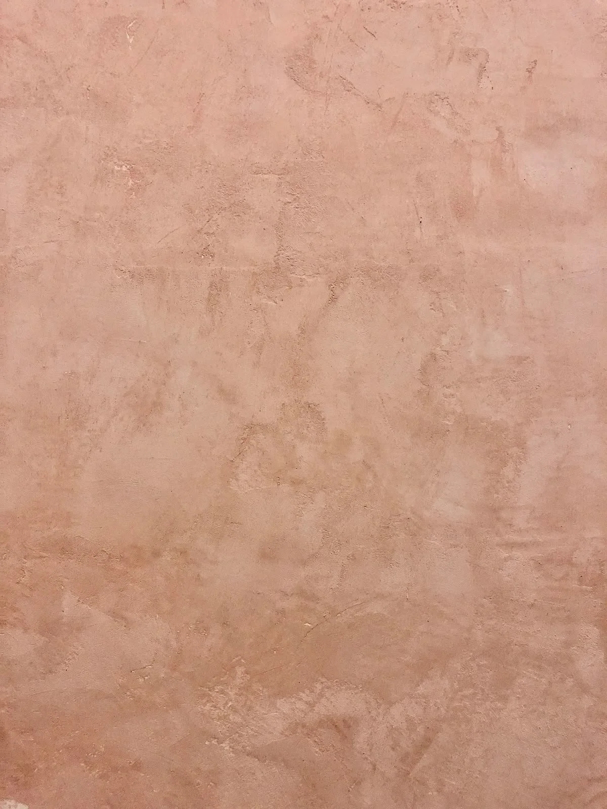 Superficie di muro in tonalità rosa con texture ruvida.