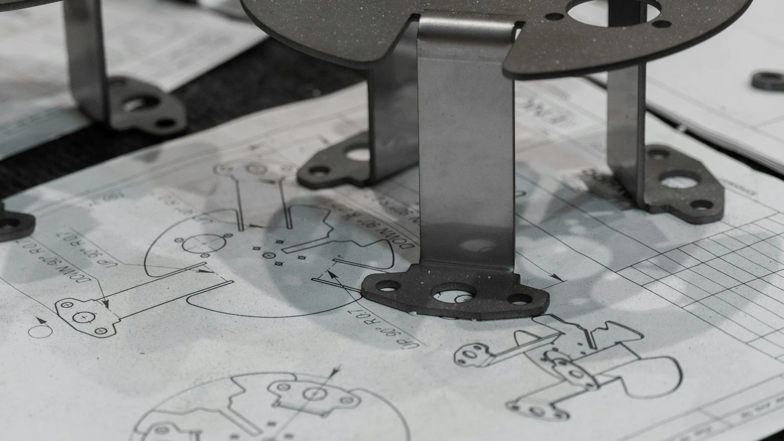Metal mechanical parts placed on a technical engineering drawing or blueprint.