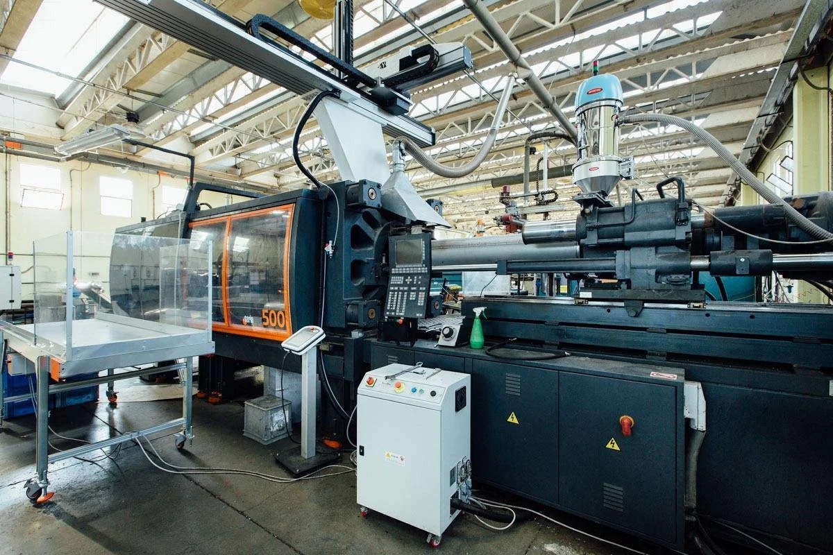 Industrial CNC machine in a spacious factory with high ceilings and large windows.