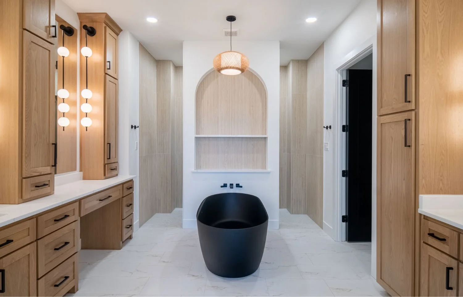 A modern bathroom featuring a freestanding black bathtub, an arched wall niche with shelving, and a woven pendant light fixture.
