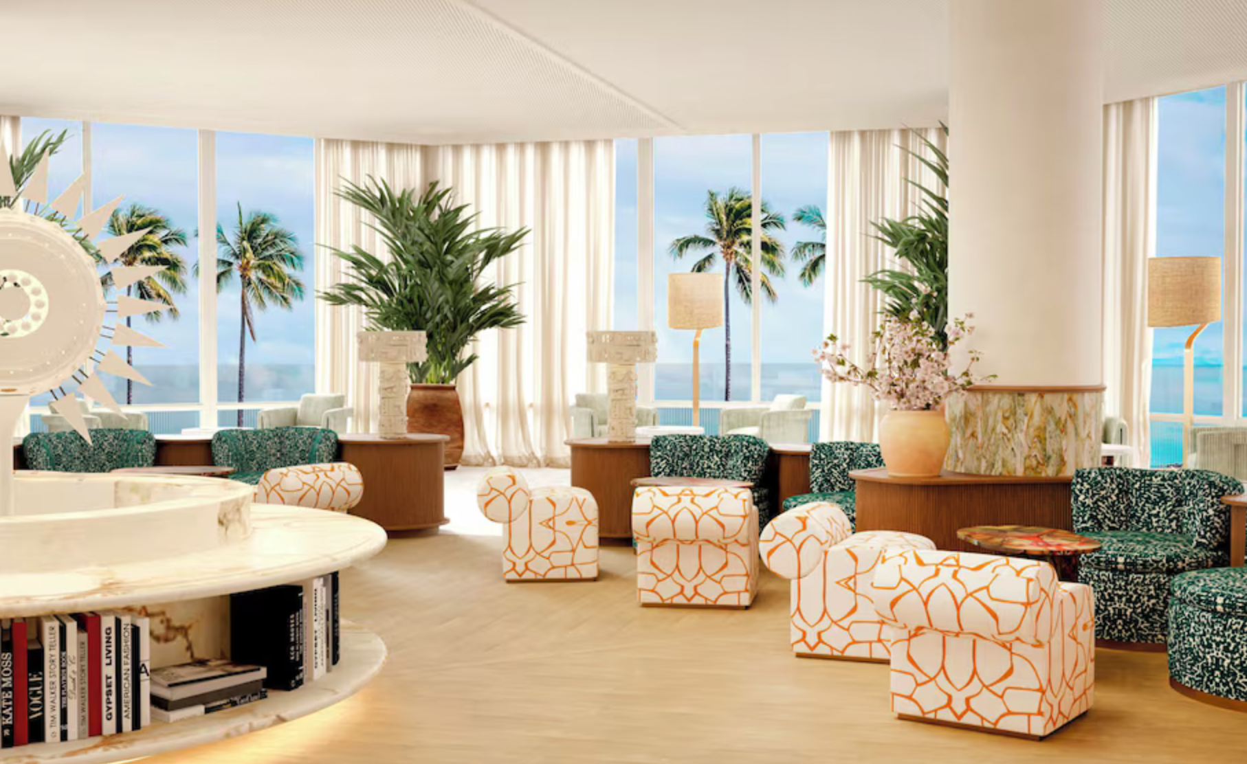 Bright hotel lobby with large windows, palm trees outside, white curtains, potted plants, patterned armchairs and ottomans, white coffee table with books, large floral vase with pink flowers, standing lamps, and modern decor.