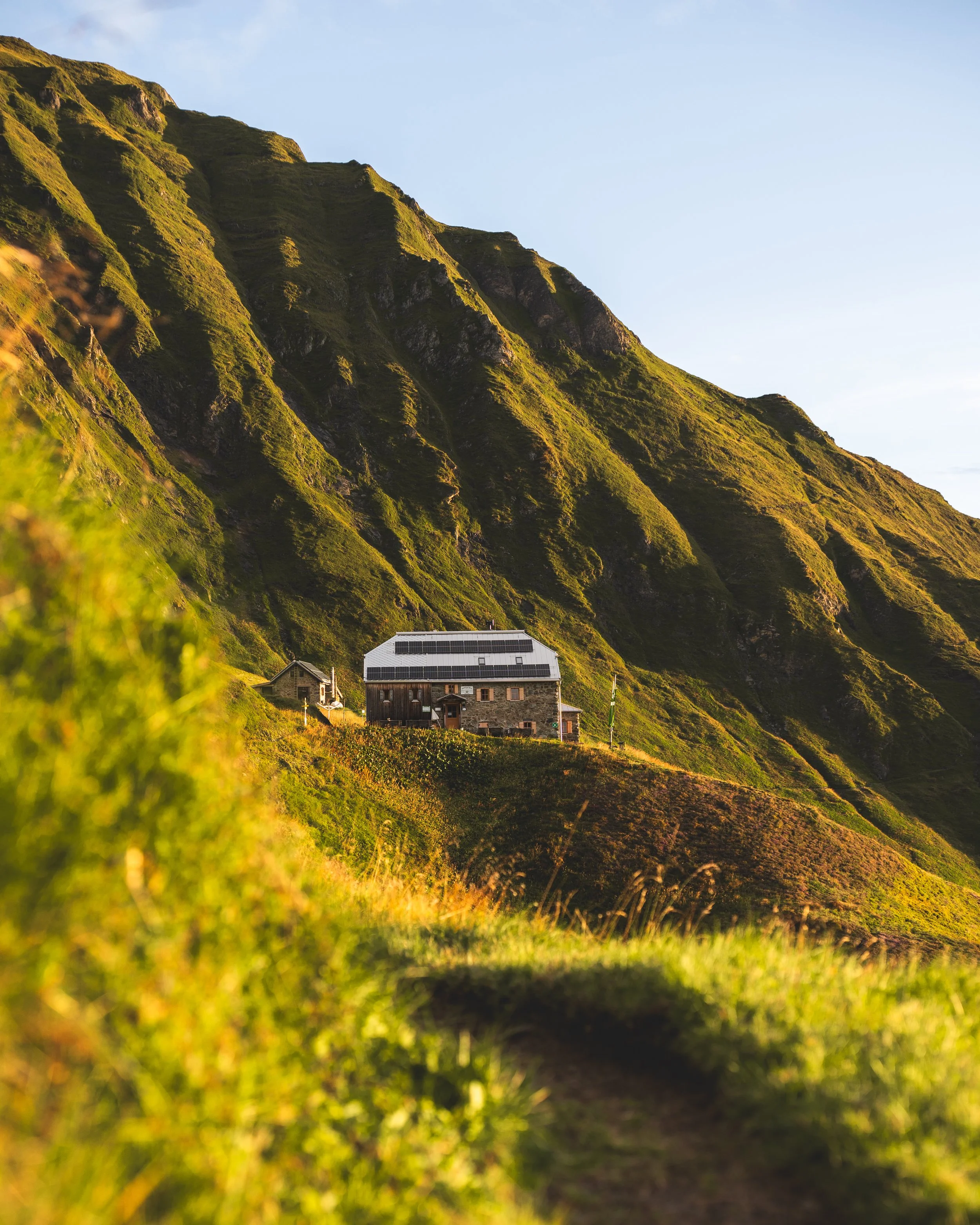 Berghütte im Morgenlicht mit grünen Wiesen